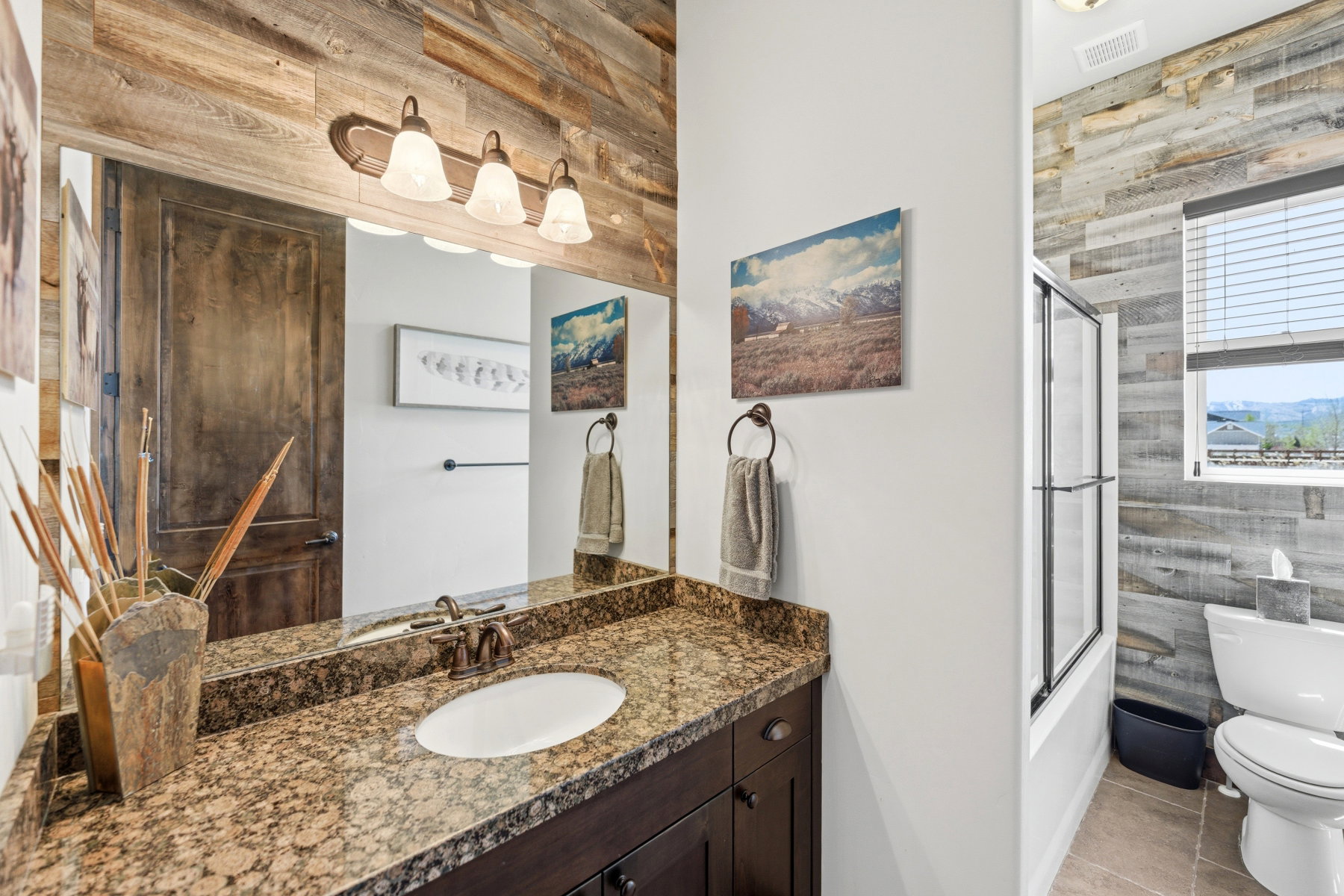 Vanity area featuring a granite countertop, undermount sink, and wood-finish cabinetry