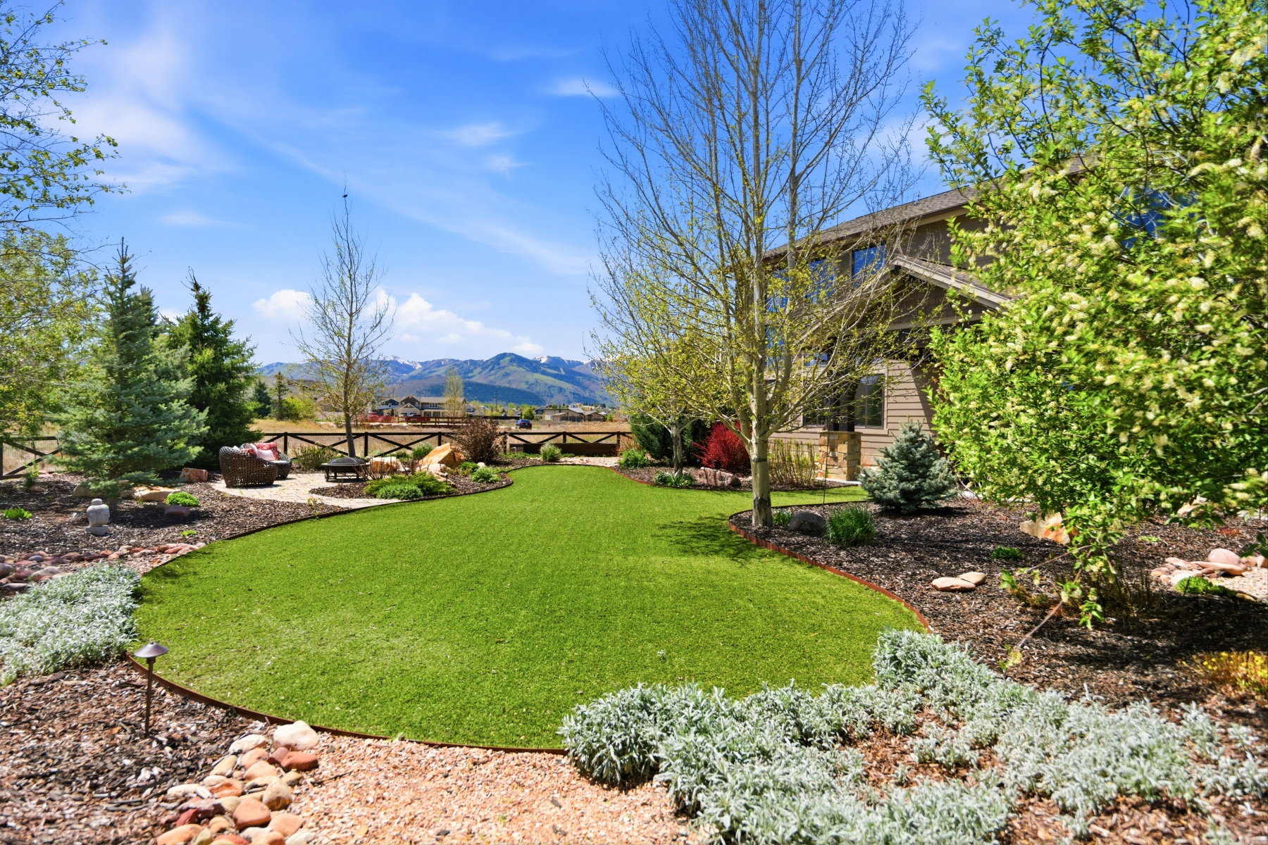 Expansive backyard featuring a manicured lawn, established landscaping, and a fenced perimeter