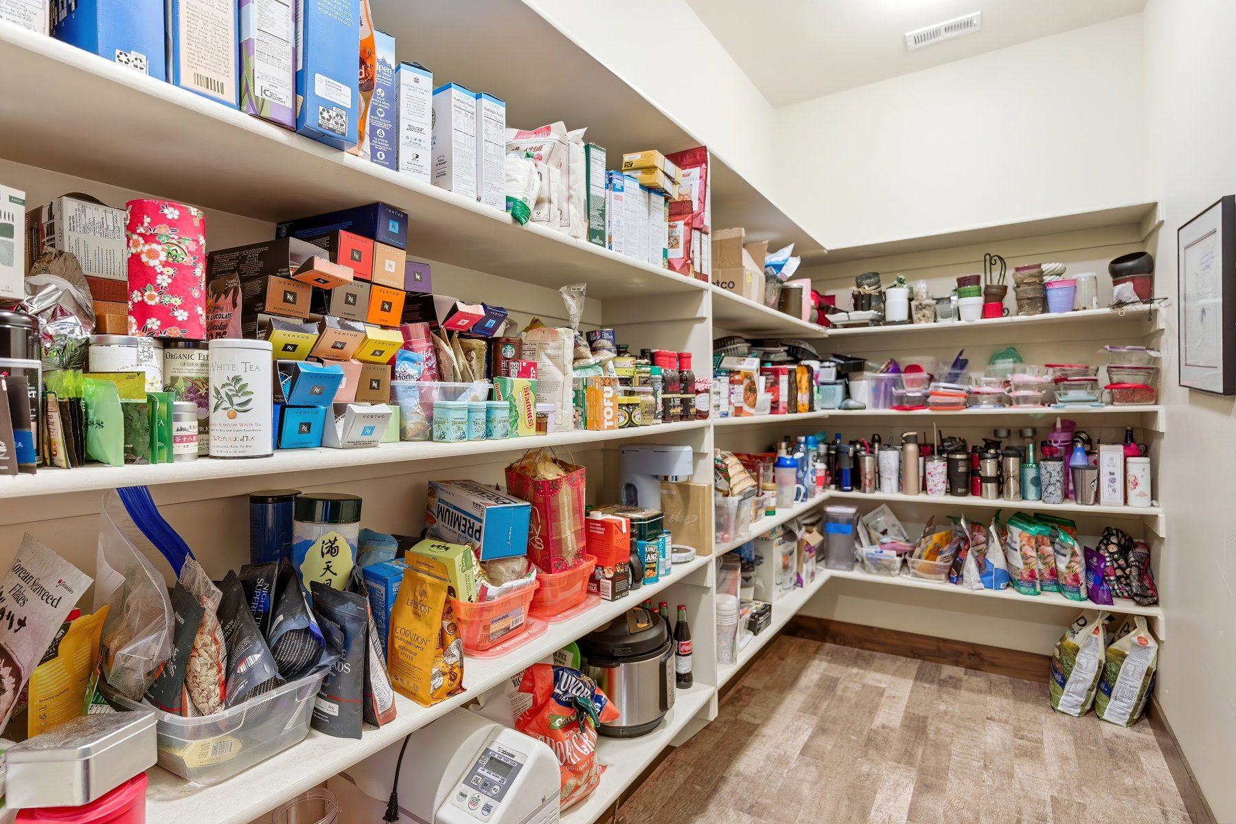 Walk-in pantry featuring extensive built-in shelving, wood-finish flooring, and recessed ceiling lighting