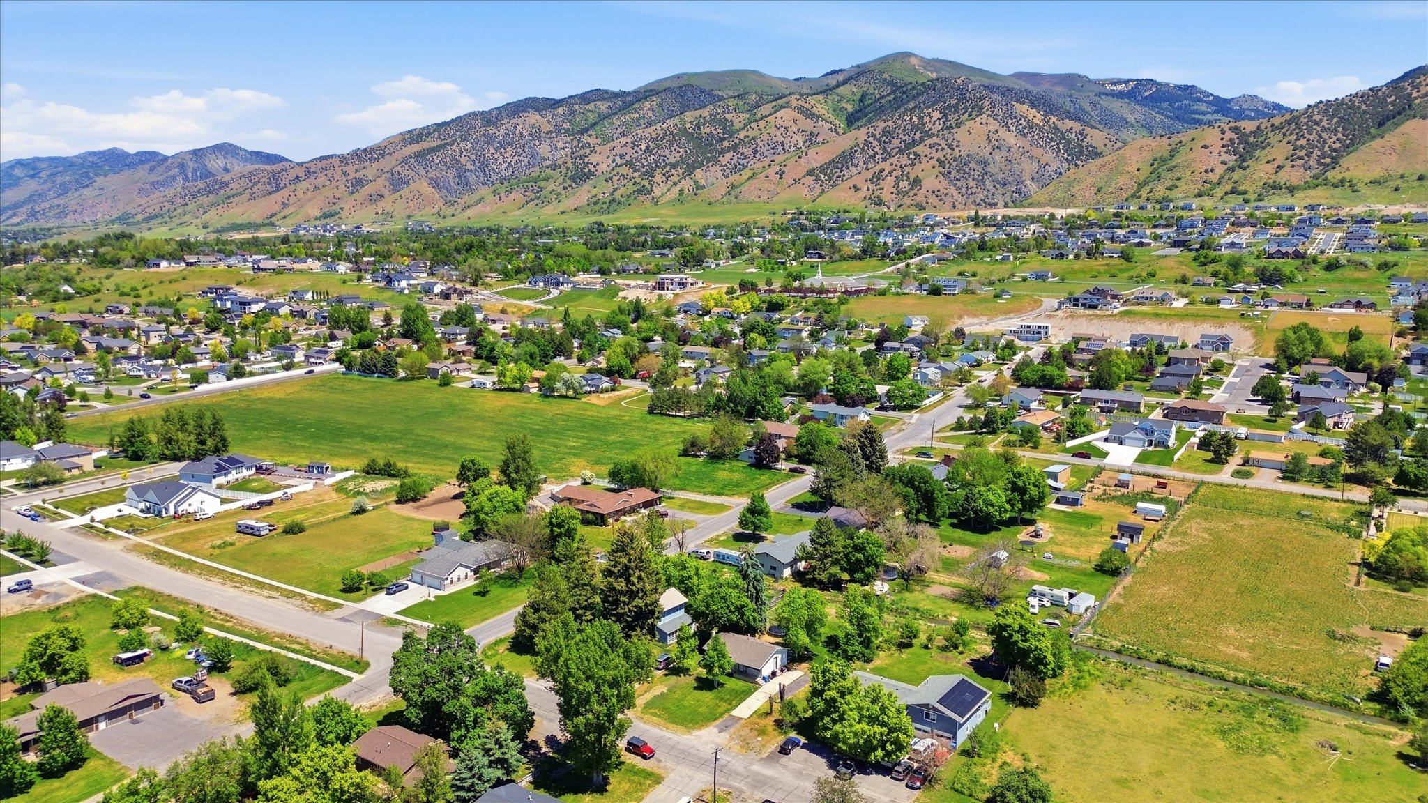 Expansive aerial landscape featuring a residential community with mature trees, established roads, and undeveloped land