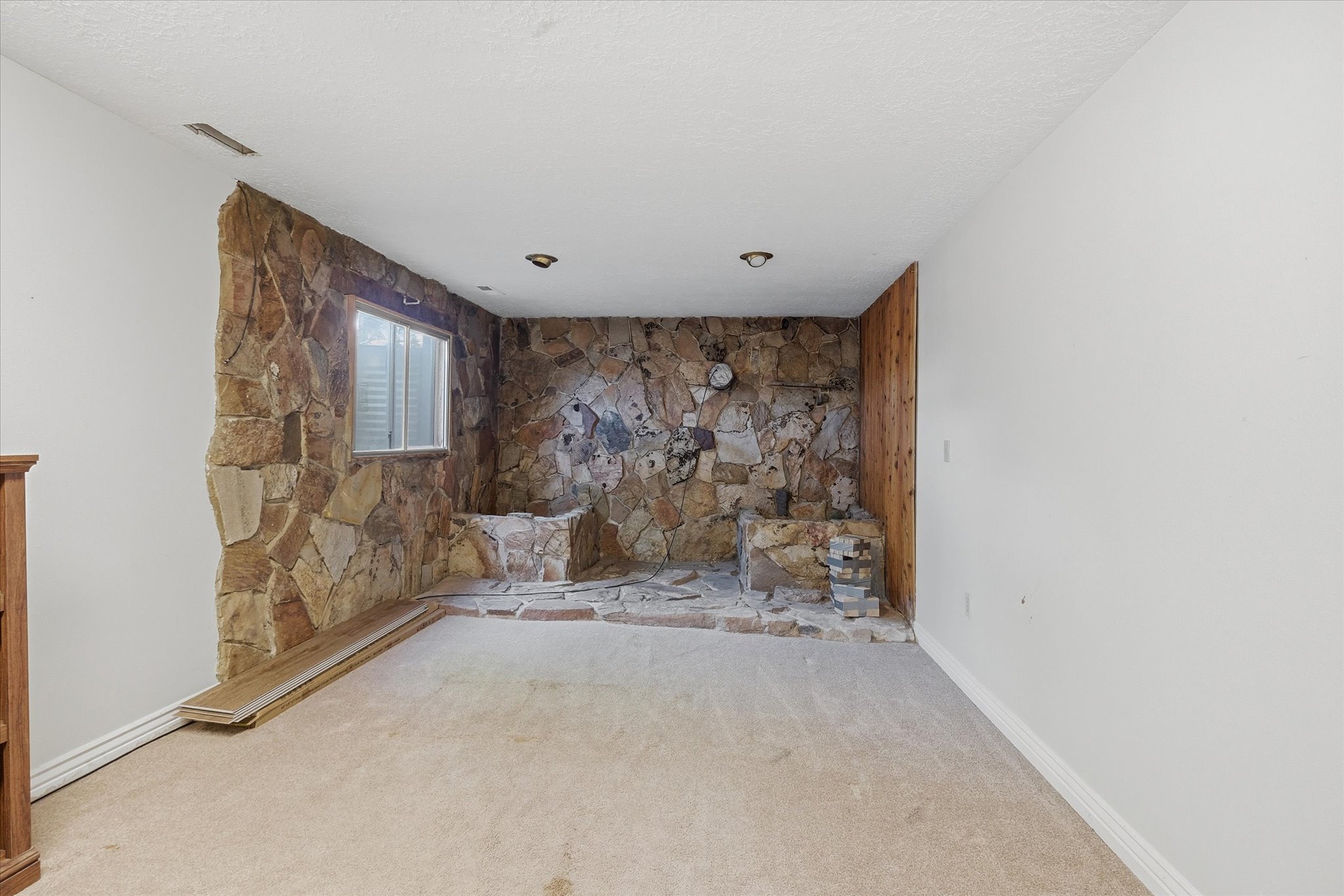 Stone accent wall featuring a partial window, built-in stone elements, and recessed ceiling lighting