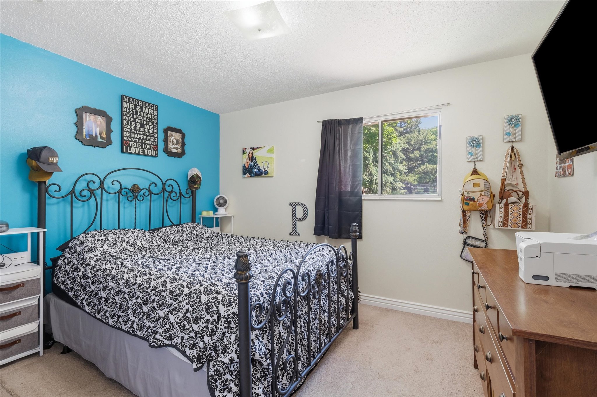 Carpeted bedroom featuring a window with natural light, a wood-finish dresser, and light-colored walls