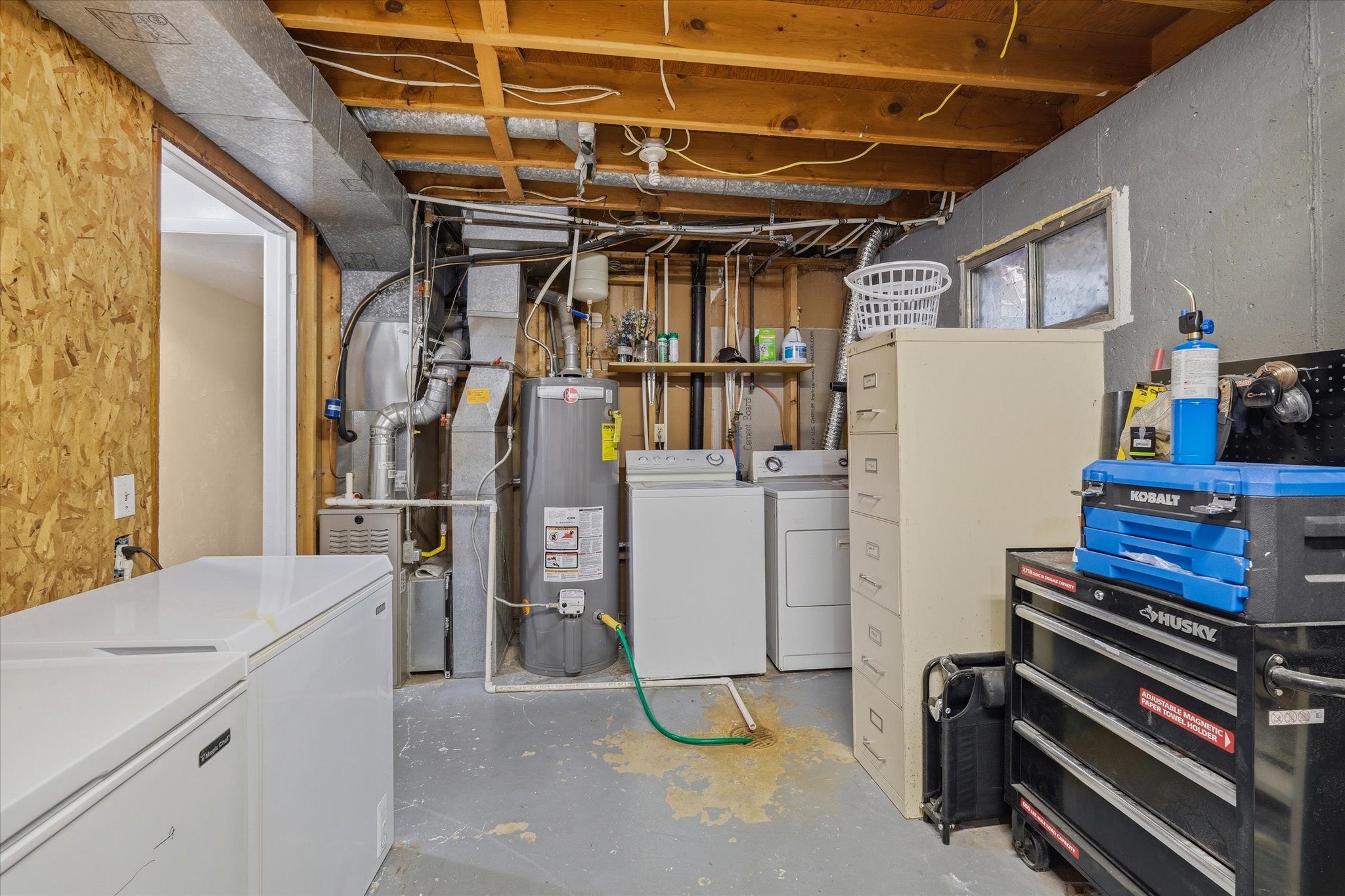 Utility space featuring exposed ceiling joists and ductwork, a water heater, and laundry appliances