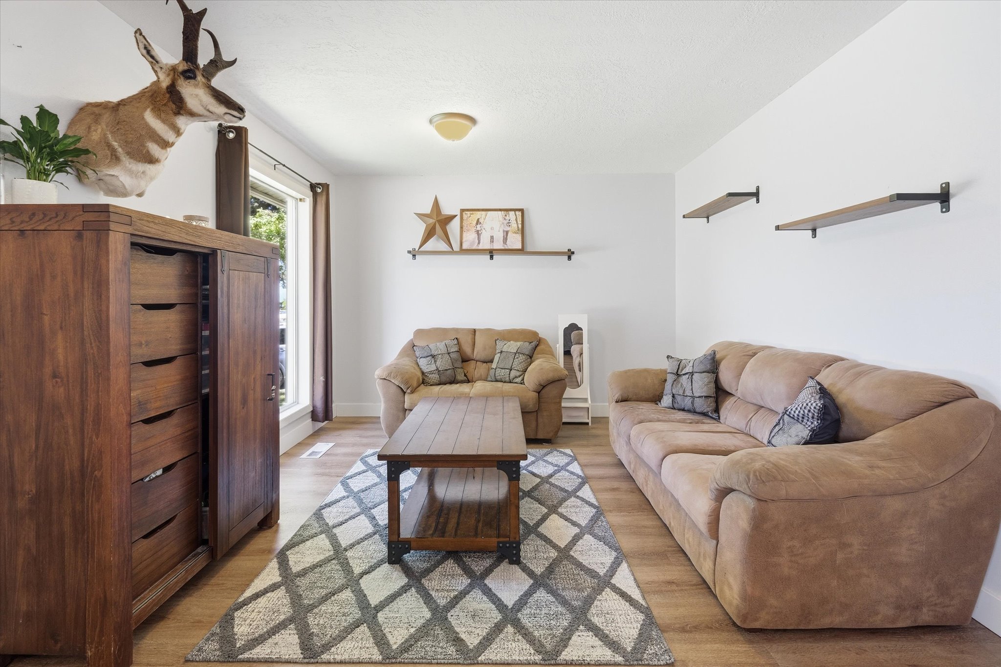 Bright living space featuring wood-finish flooring, white walls, and a prominent window providing natural light