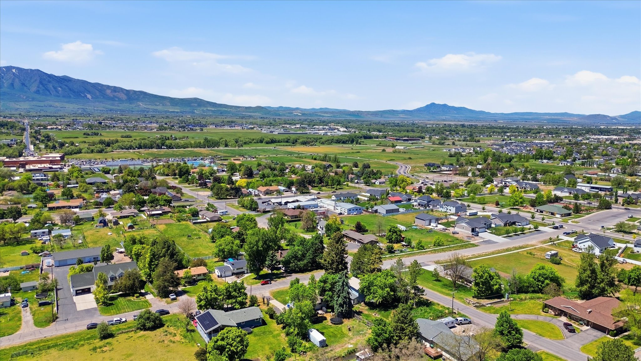 Expansive aerial perspective showcasing a residential landscape with varied housing styles, verdant trees, and broad agricultural areas