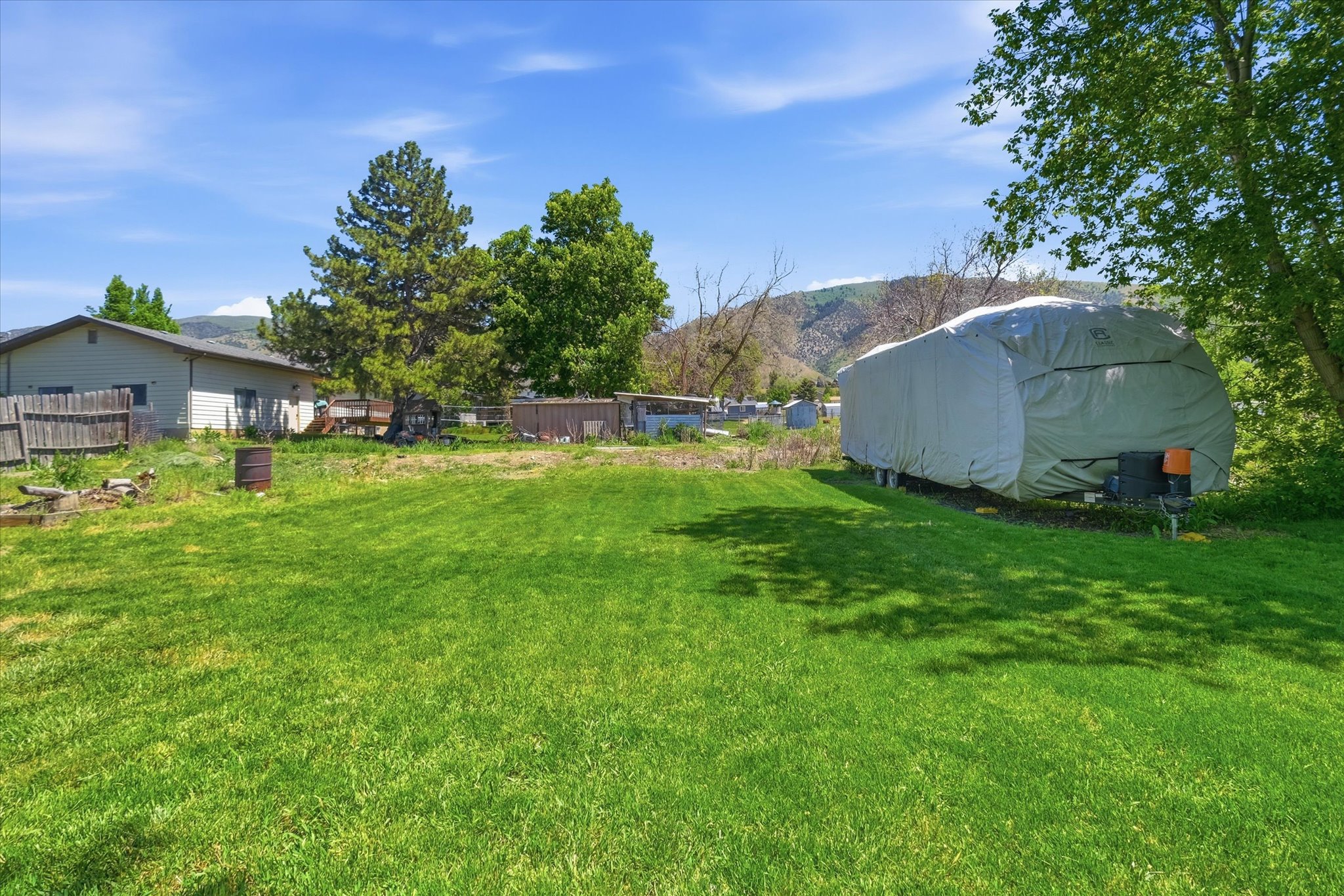 Expansive grassy yard with mature trees providing partial shade
