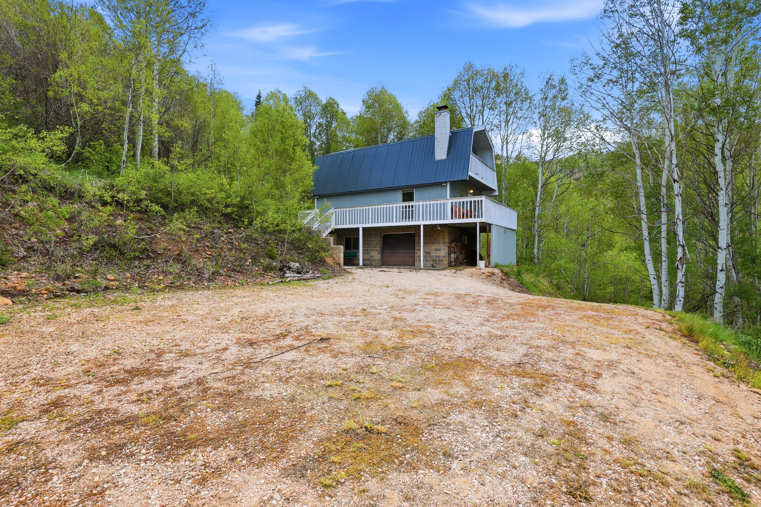 Two-story residence featuring a blue metal roof, light blue siding, and a stone-clad lower level