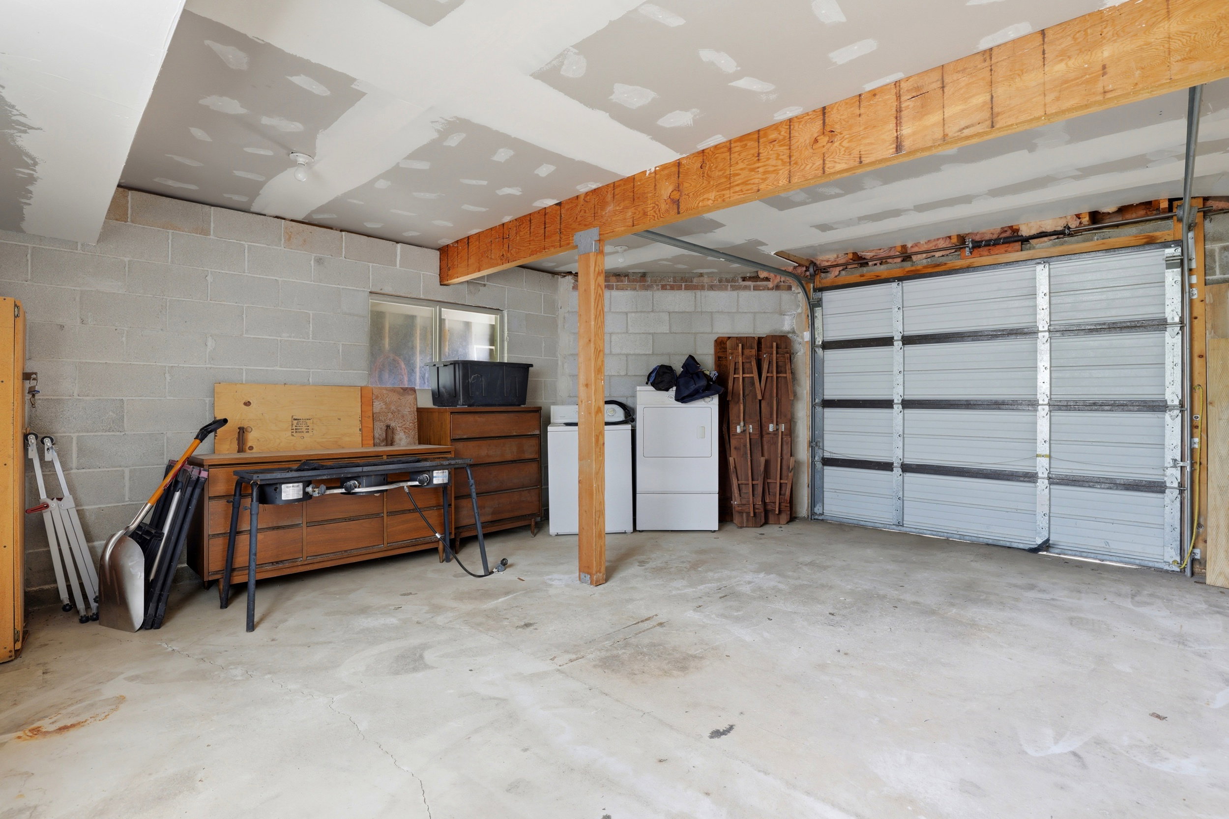 Spacious garage with concrete block walls, exposed wood ceiling joists, and a sectional overhead door