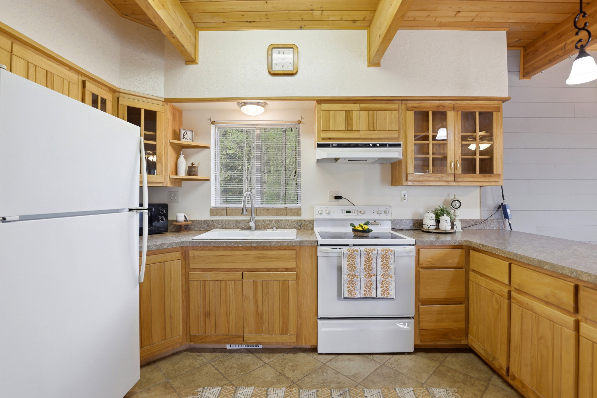 Kitchen featuring wood cabinetry, laminate countertops, a white top-freezer refrigerator, and a white electric range