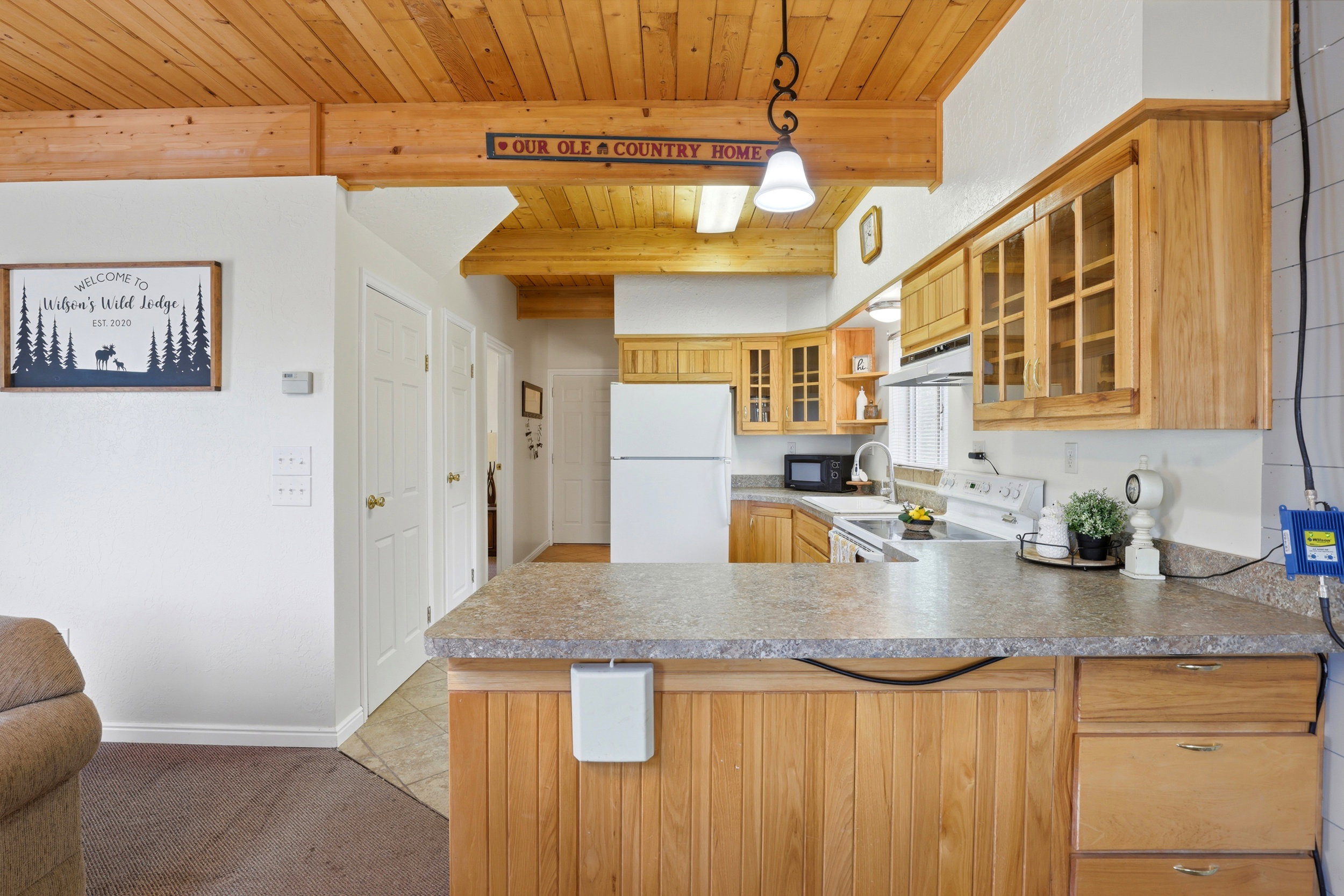 Kitchen featuring a wood-panel breakfast bar with an integrated countertop, wood cabinetry with glass-front uppers, and stainless steel appliances