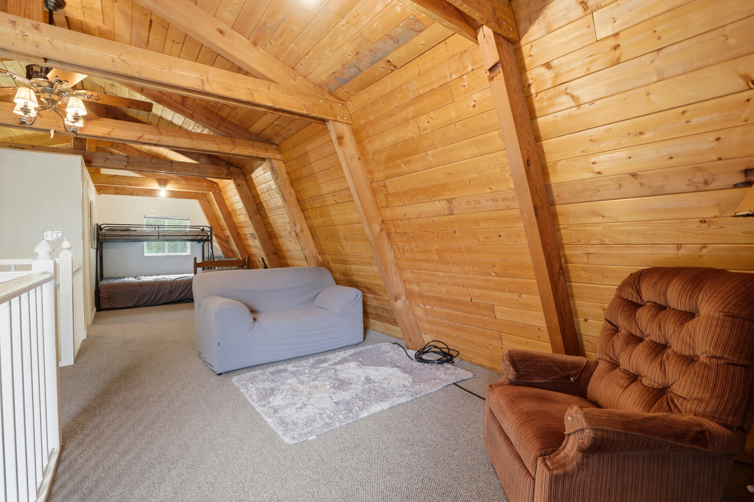 Open loft area featuring exposed wood beams and wood-paneled walls