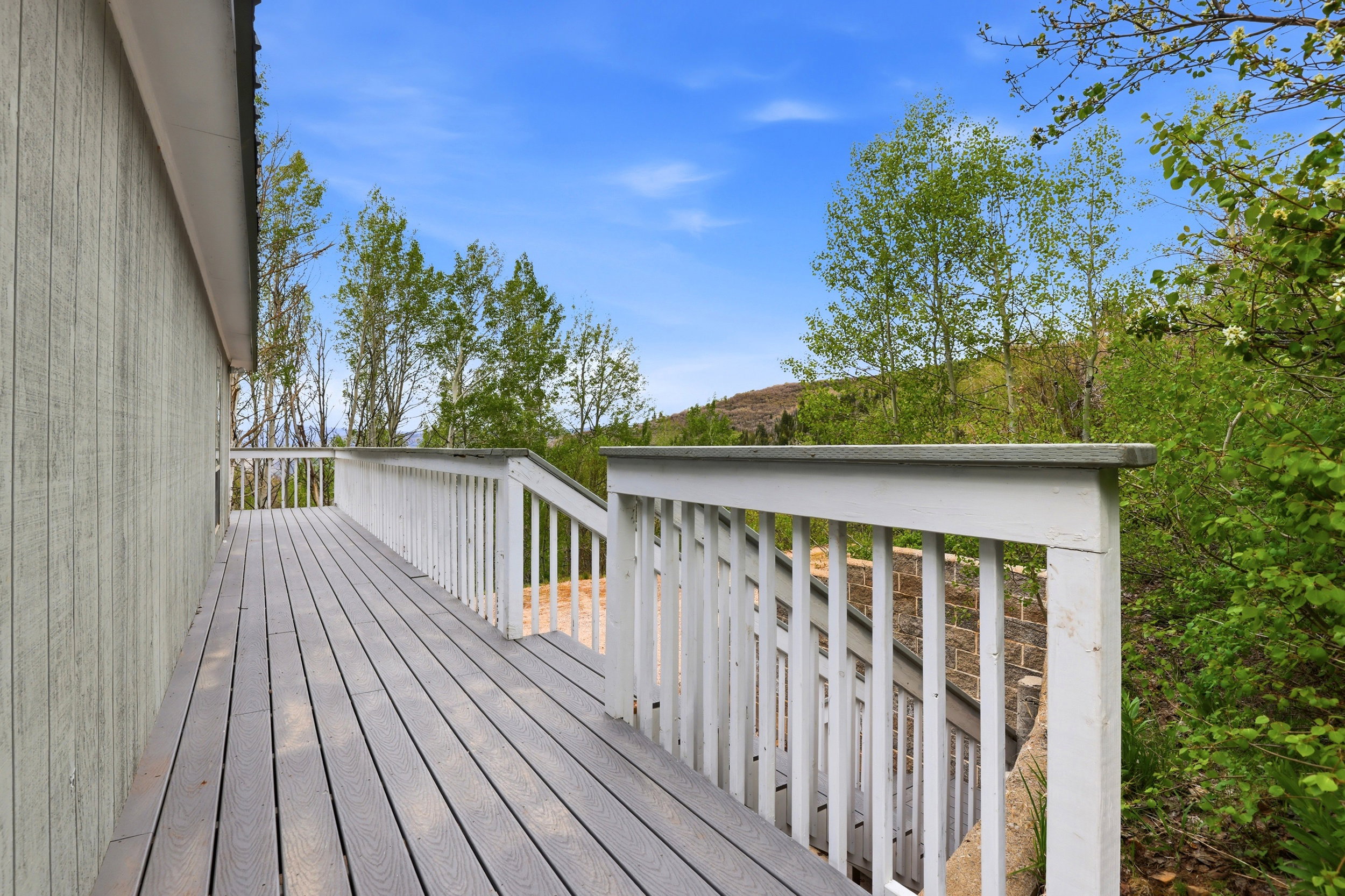 Expansive outdoor deck featuring wood-finish flooring and white railings