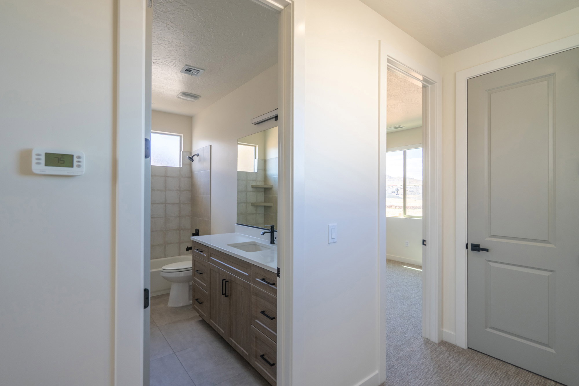 Full bathroom featuring a wood-finish vanity with a white countertop and rectangular undermount sink