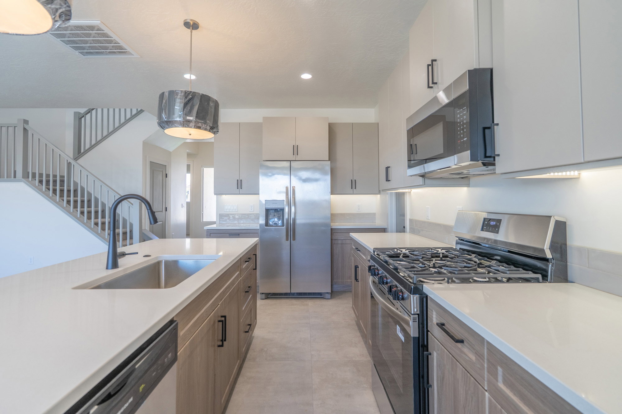 Modern kitchen featuring stainless steel appliances, light-toned cabinetry, and quartz countertops