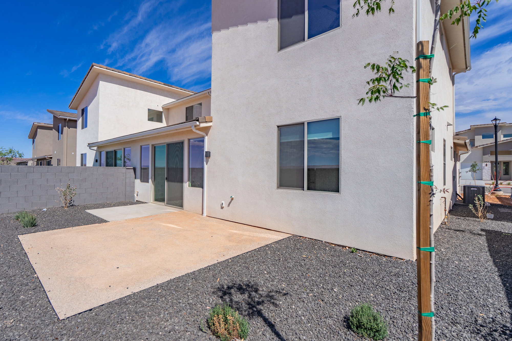 Rear exterior showcasing a concrete patio, sliding glass doors, and a block wall perimeter
