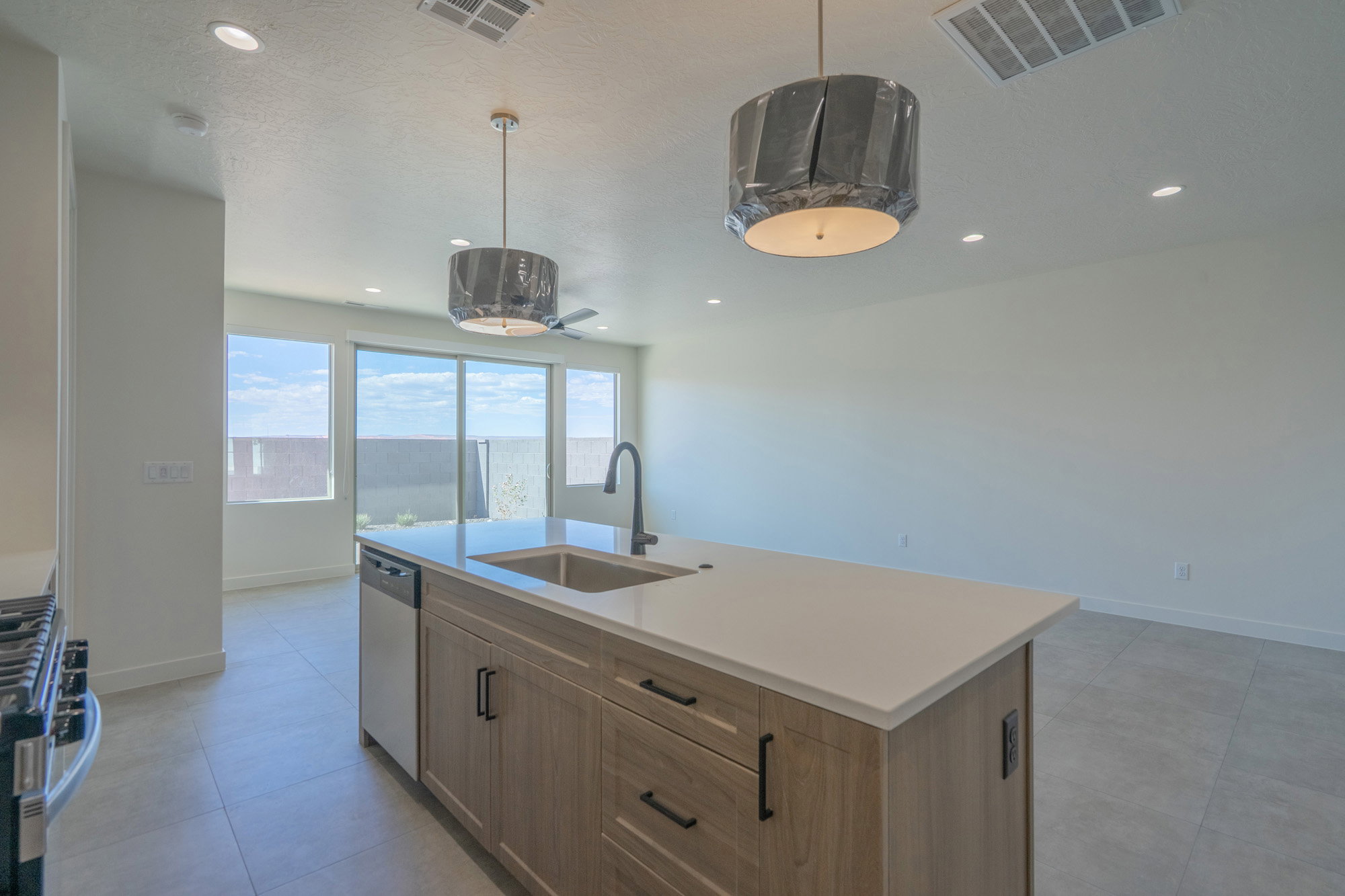 Spacious kitchen island featuring a light-toned countertop, integrated sink with a matte black faucet, and wood-finish cabinetry