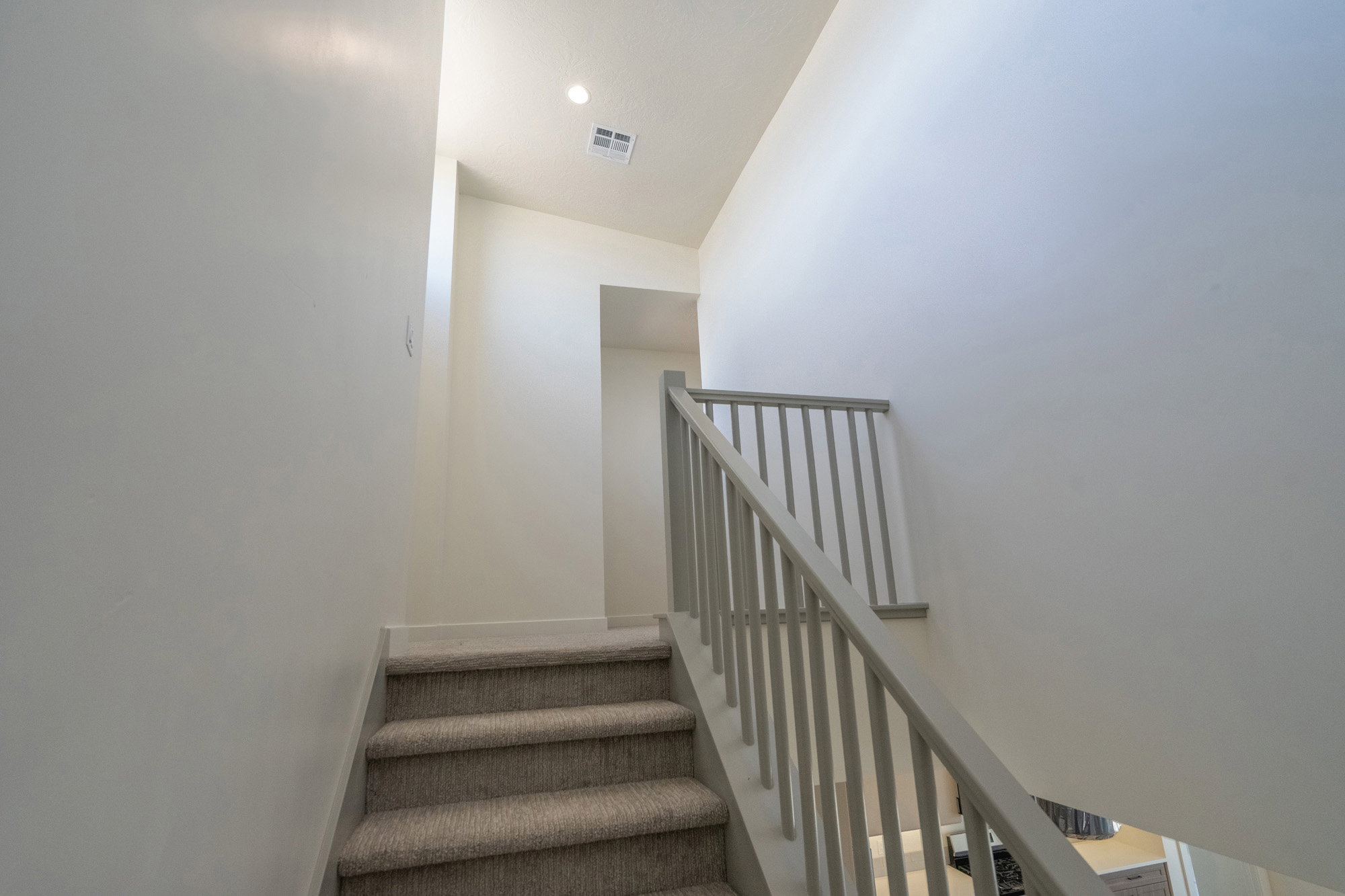 Carpeted staircase with a light gray railing