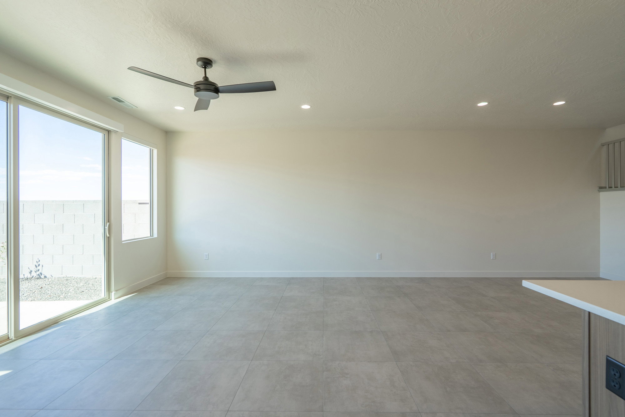 Spacious living area featuring large format tile flooring, recessed lighting, and a modern ceiling fan