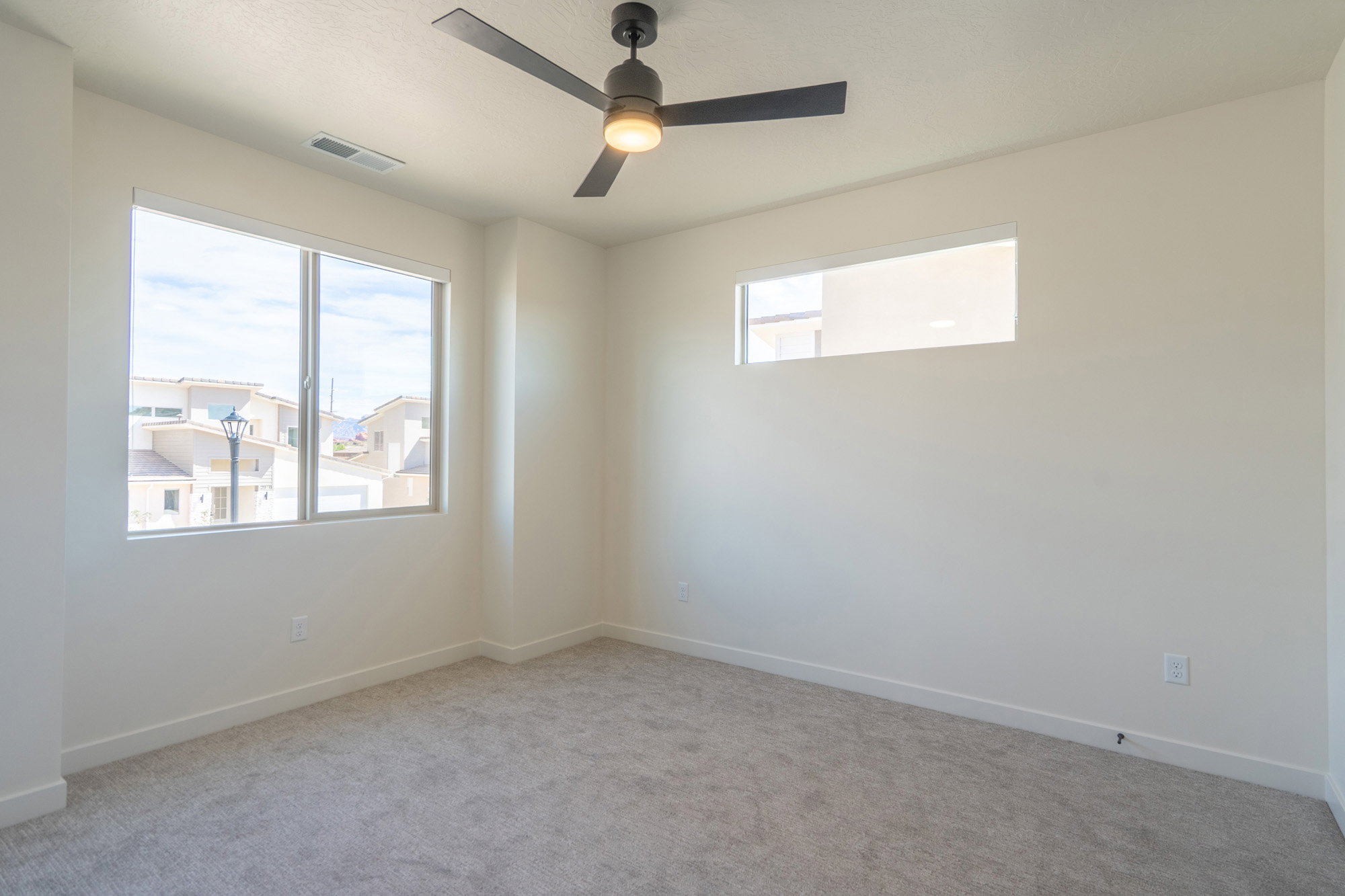 Carpeted room featuring a modern ceiling fan with integrated lighting, a large window, and an additional horizontal transom window