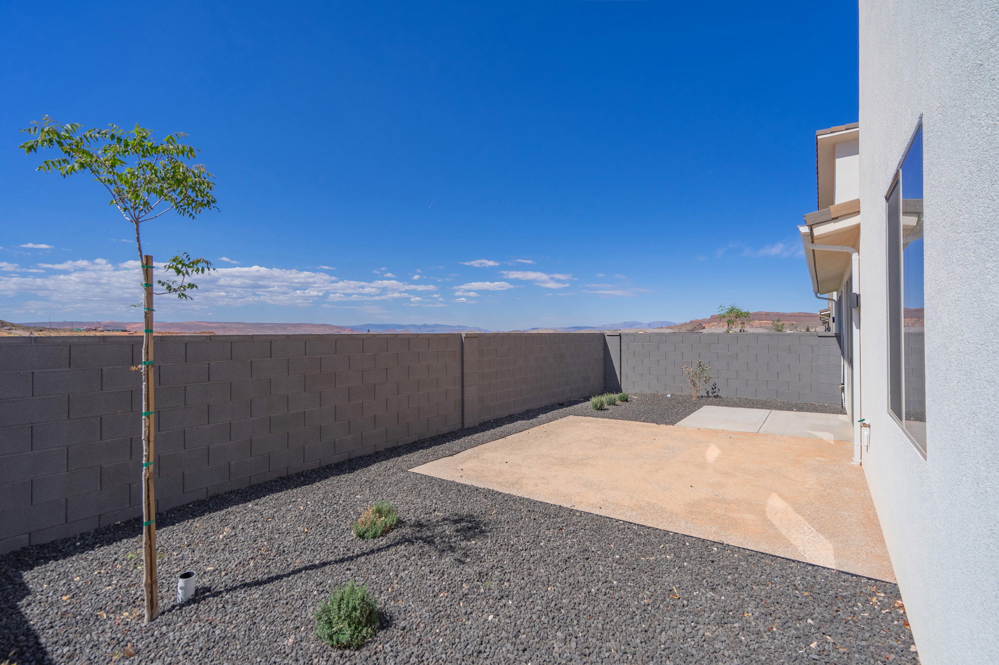 Backyard featuring a concrete patio, dark aggregate ground cover, and a block wall perimeter