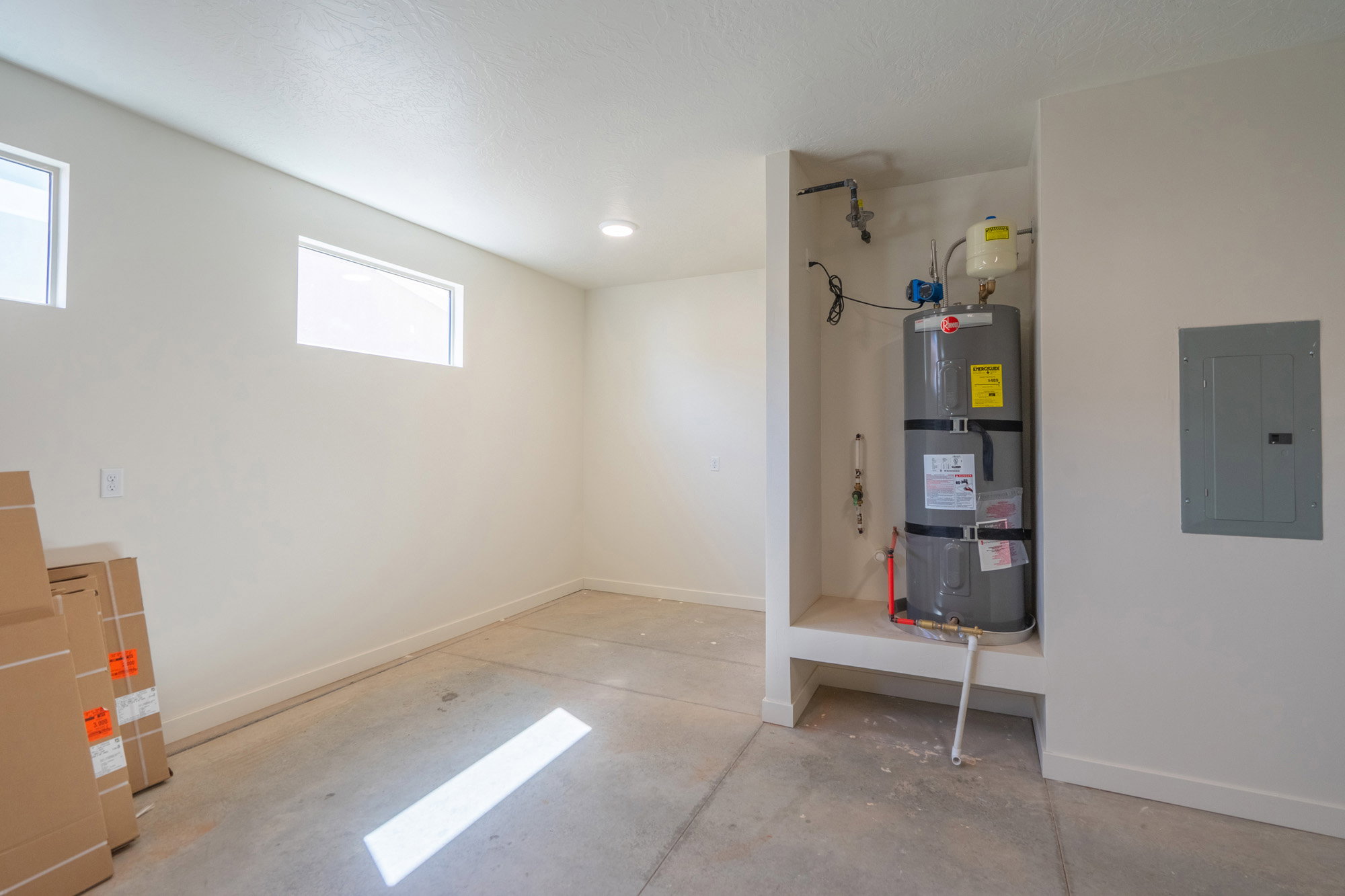 Utility area with a water heater installed in a dedicated alcove and a visible electrical panel