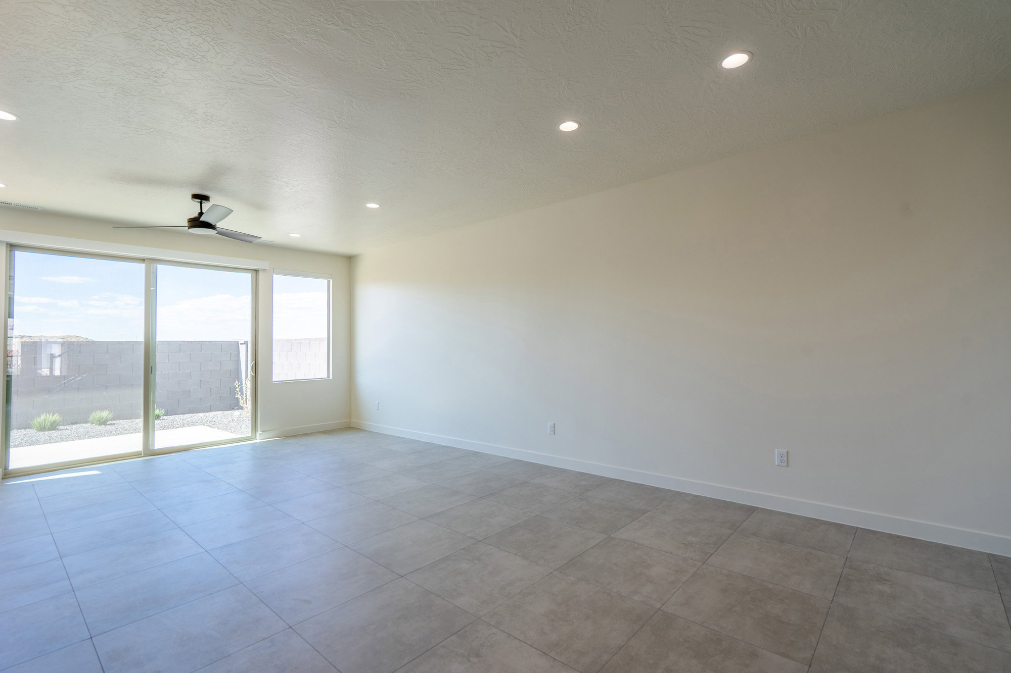 Spacious room featuring large format tile flooring, recessed lighting, and a ceiling fan