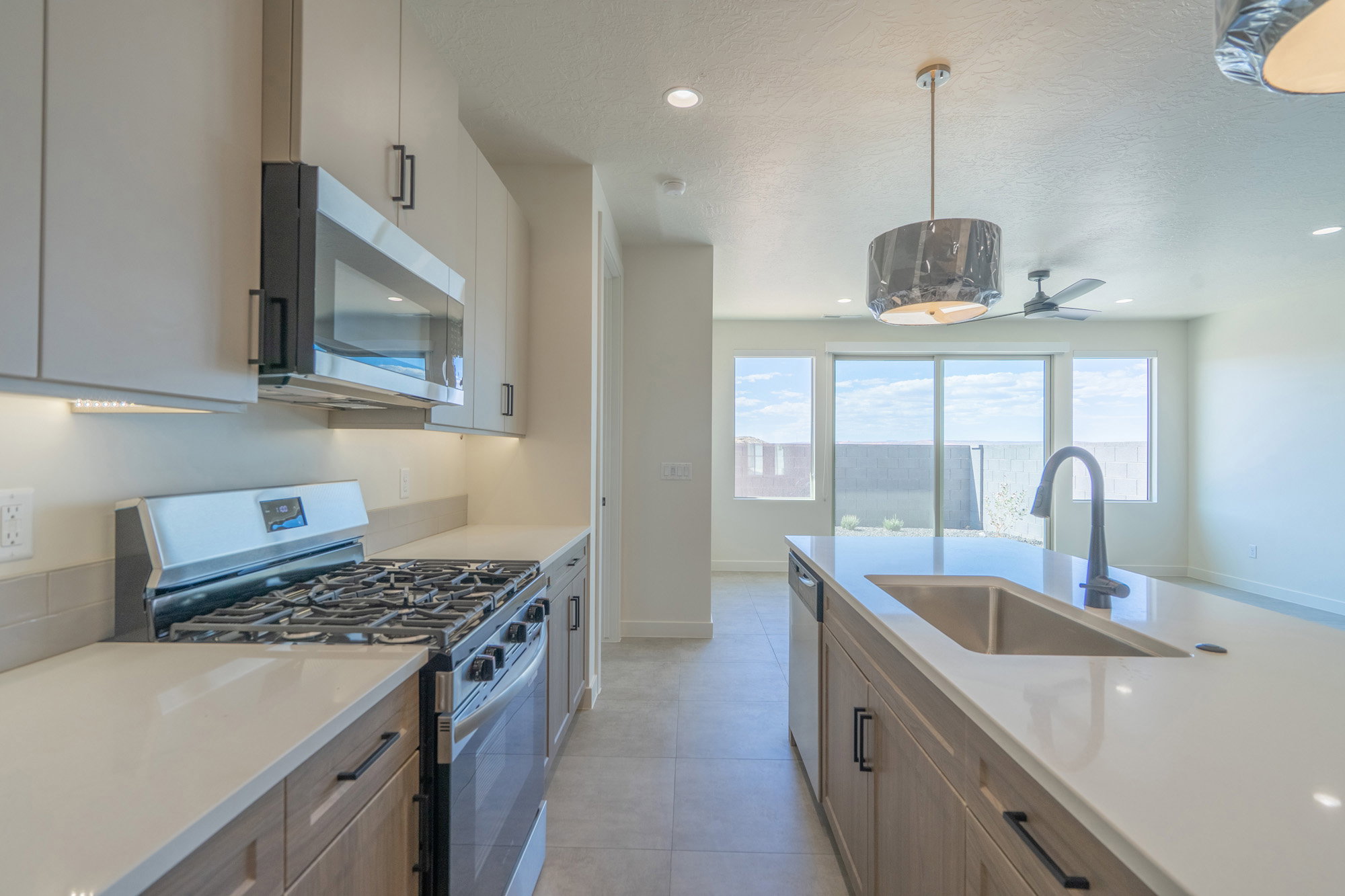 Modern kitchen featuring a stainless steel gas range, over-range microwave, and under-cabinet lighting