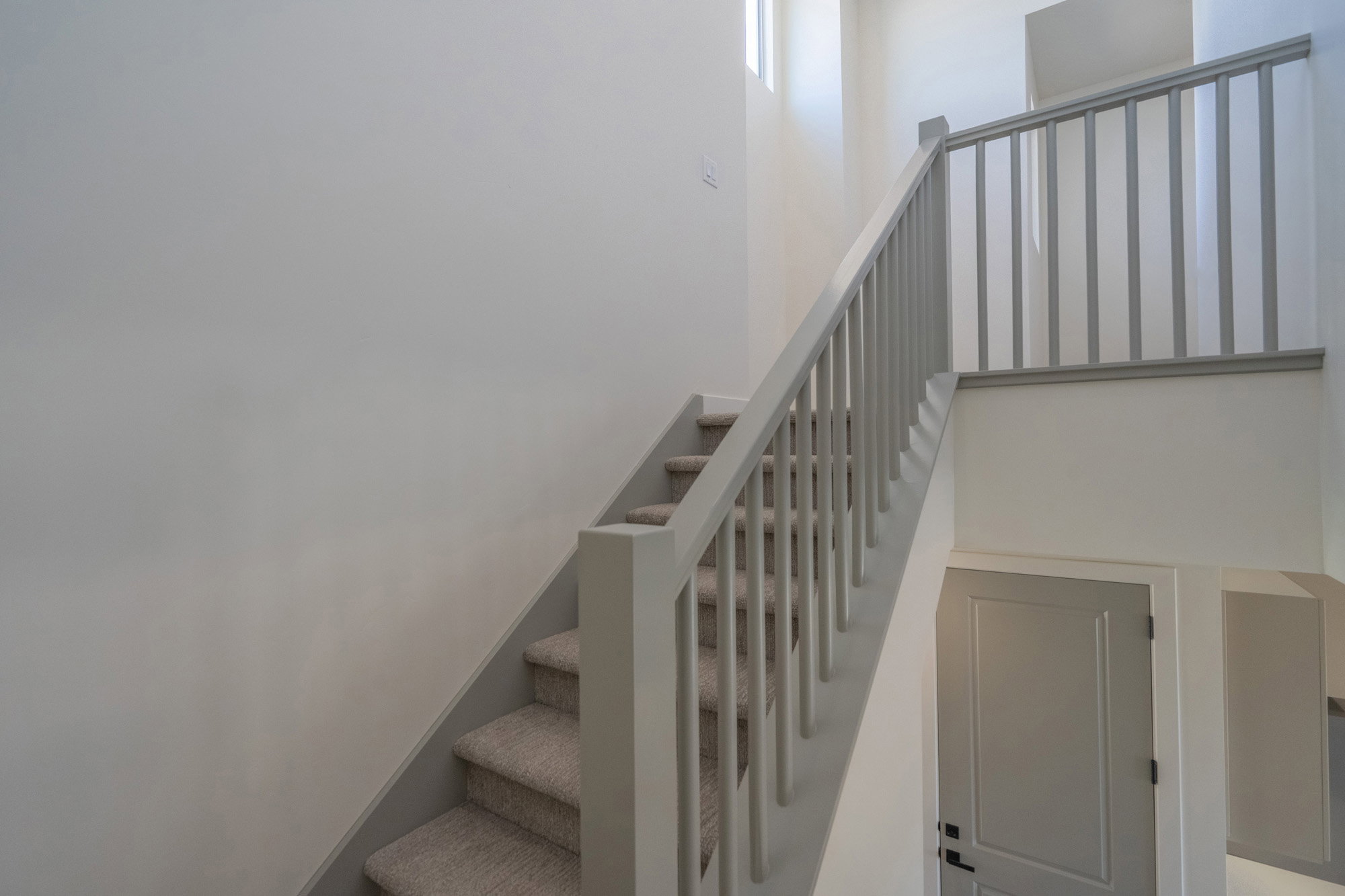 Carpeted staircase featuring a light gray baluster and handrail system