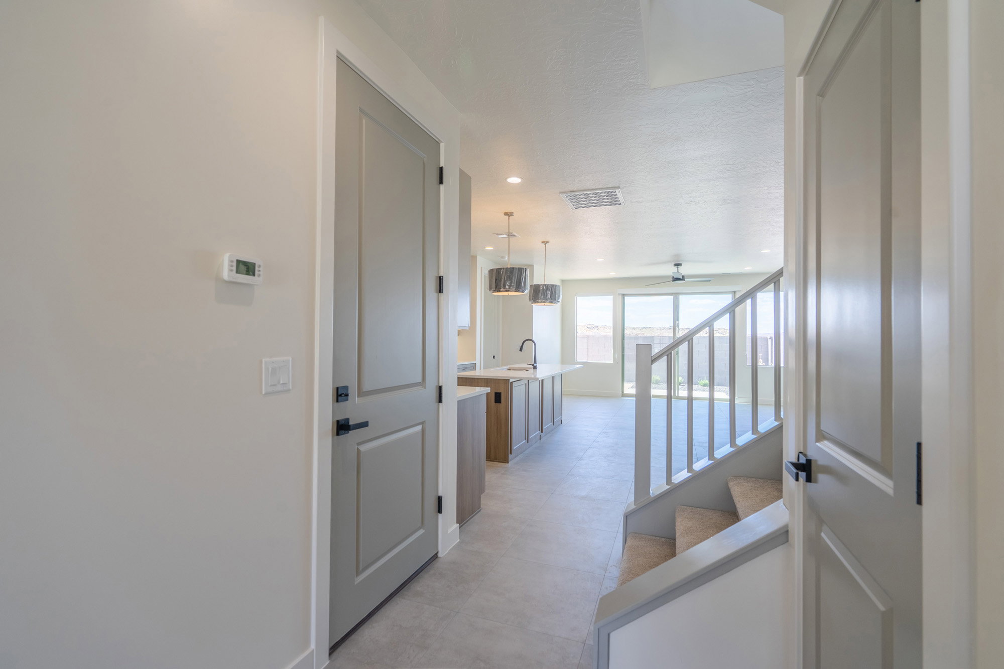 Entryway featuring a modern gray door with black hardware, a light gray wall, and a programmable thermostat