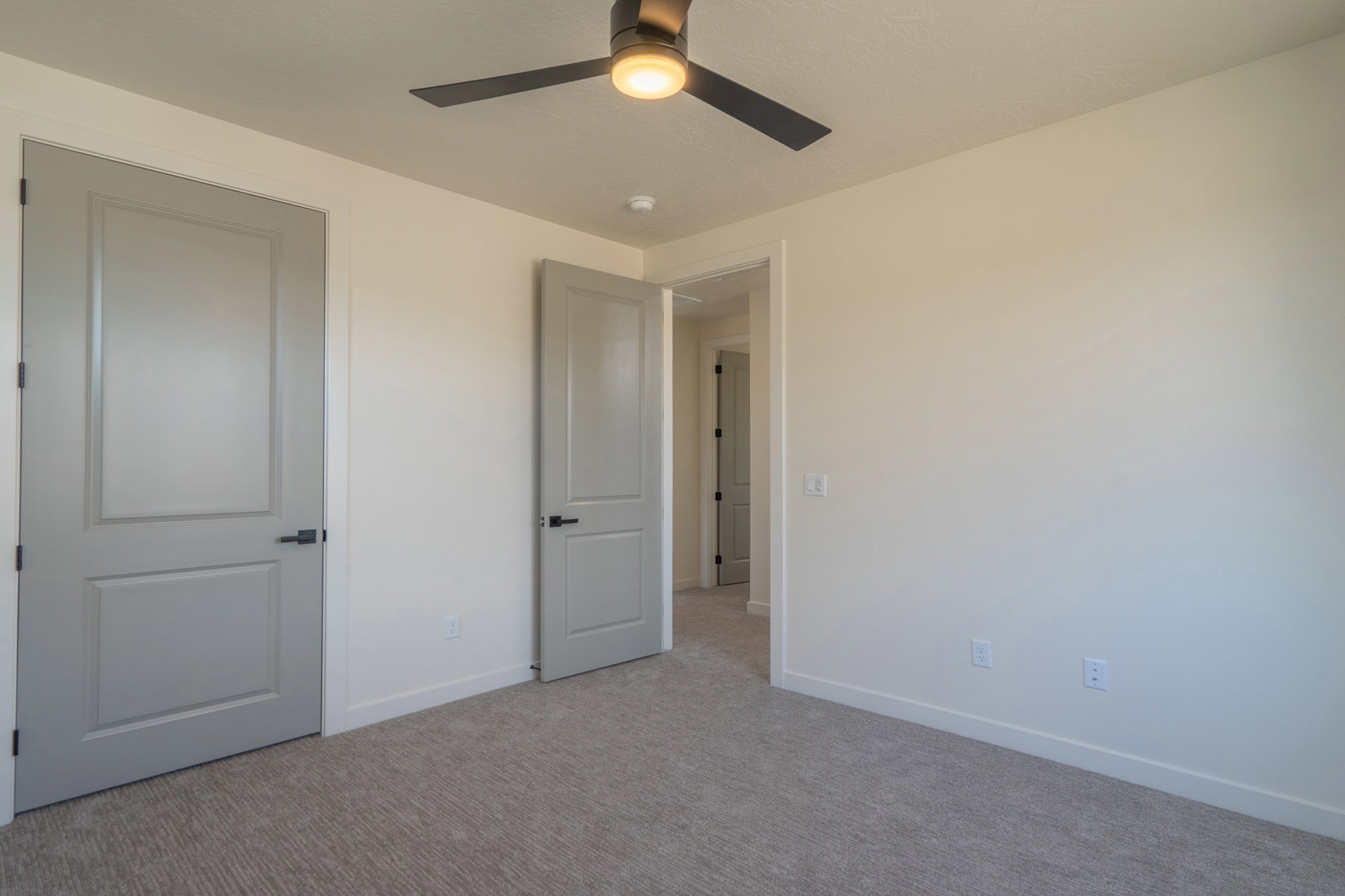 Carpeted room featuring light-colored walls and a ceiling fan with integrated lighting