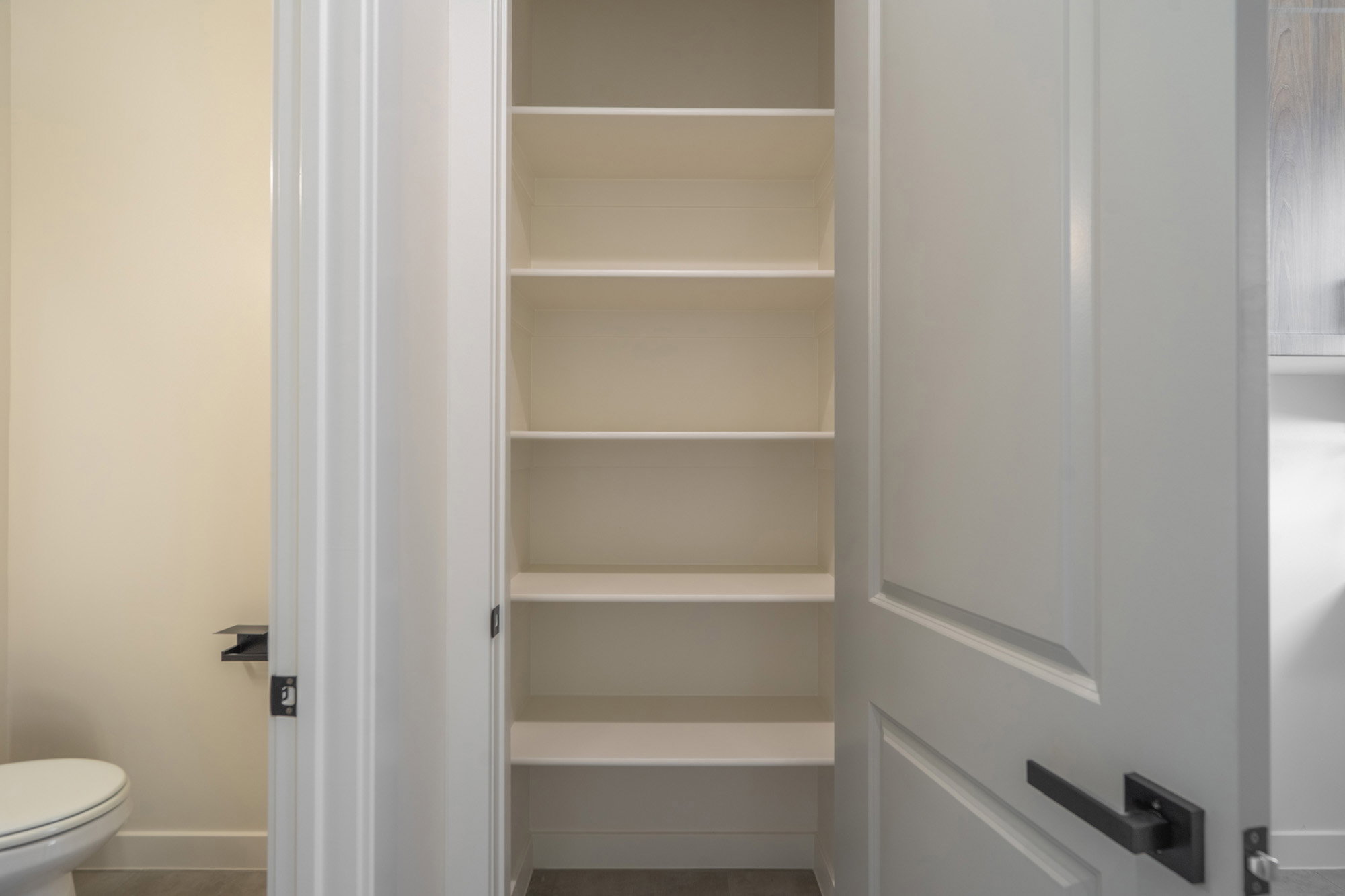Built-in shelving unit featuring multiple open shelves, white panel doors, and matte black hardware