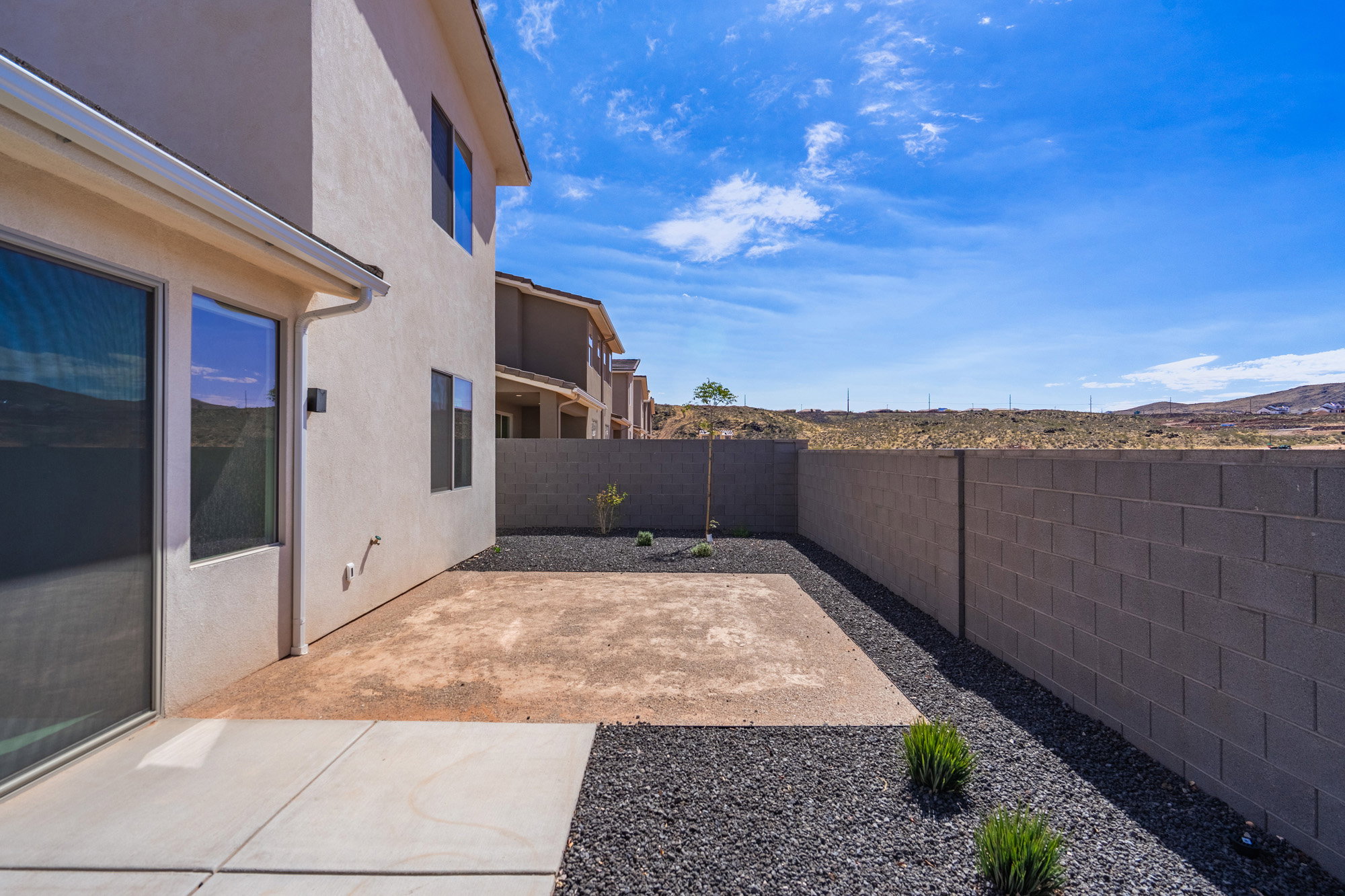 Outdoor patio area featuring a concrete slab, dark gravel landscaping, and a block wall perimeter