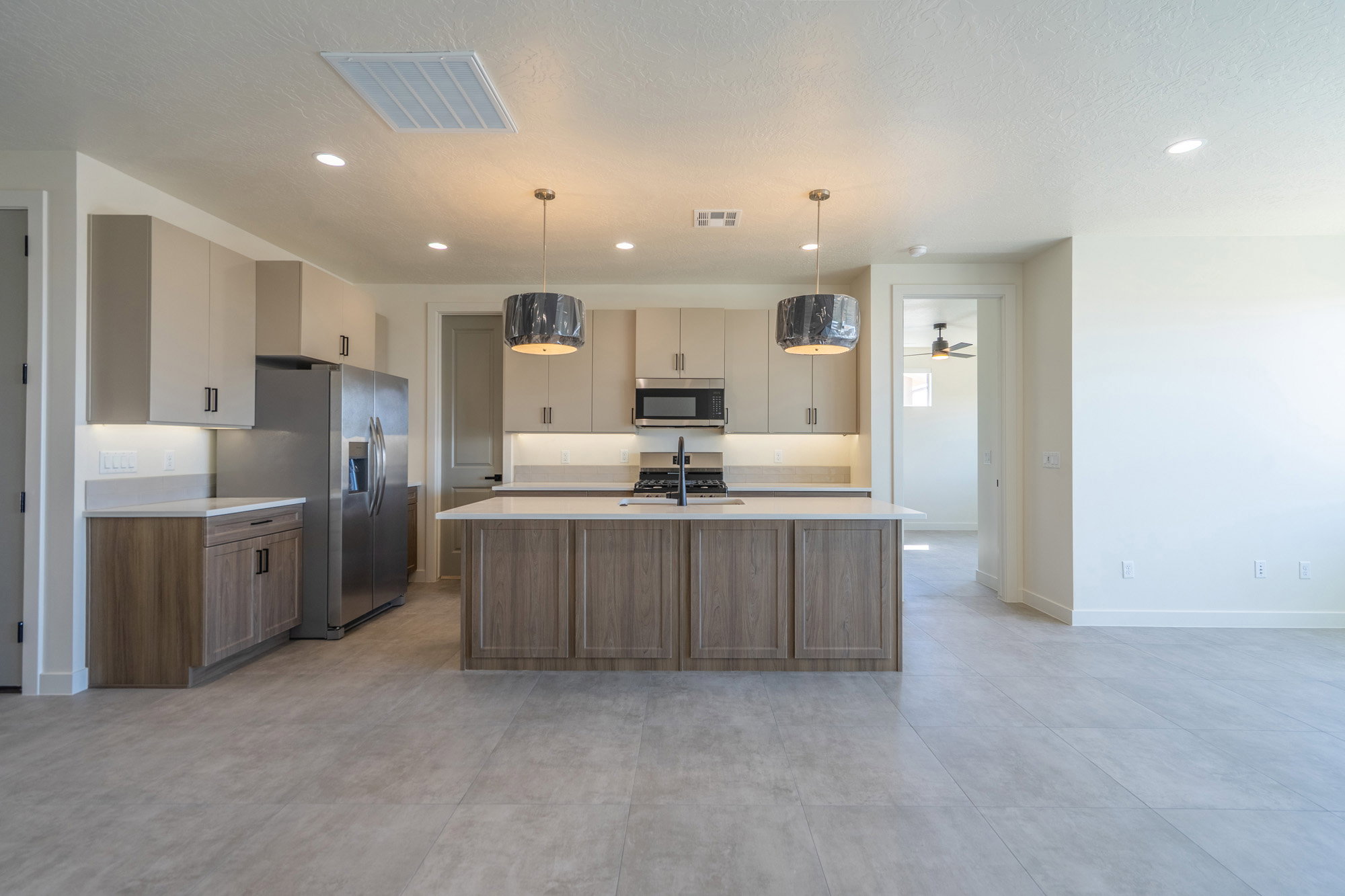 Contemporary kitchen featuring a large center island with a sink, stainless steel appliances, and overhead pendant lighting