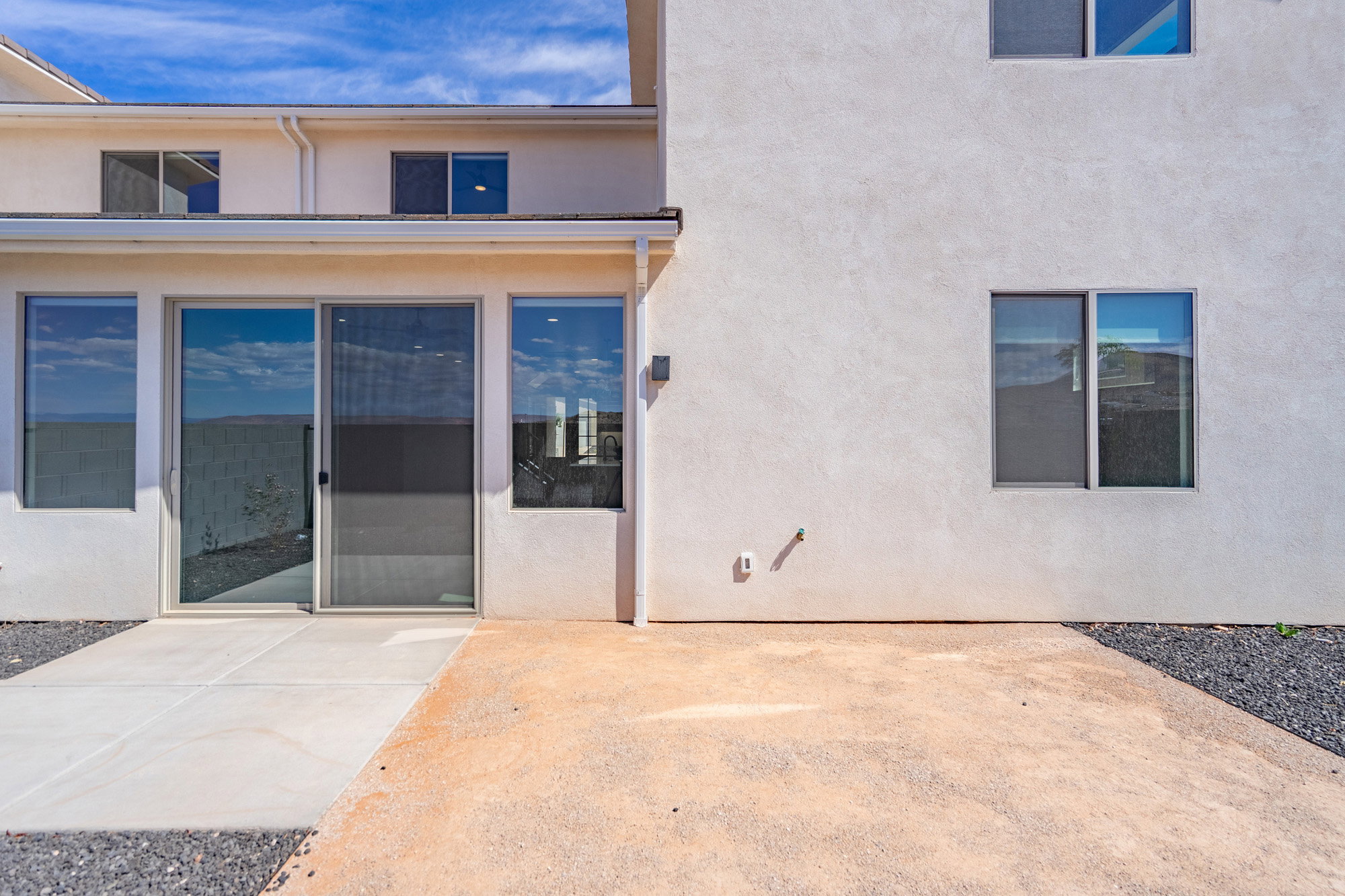 Rear patio area featuring a concrete slab and gravel landscaping