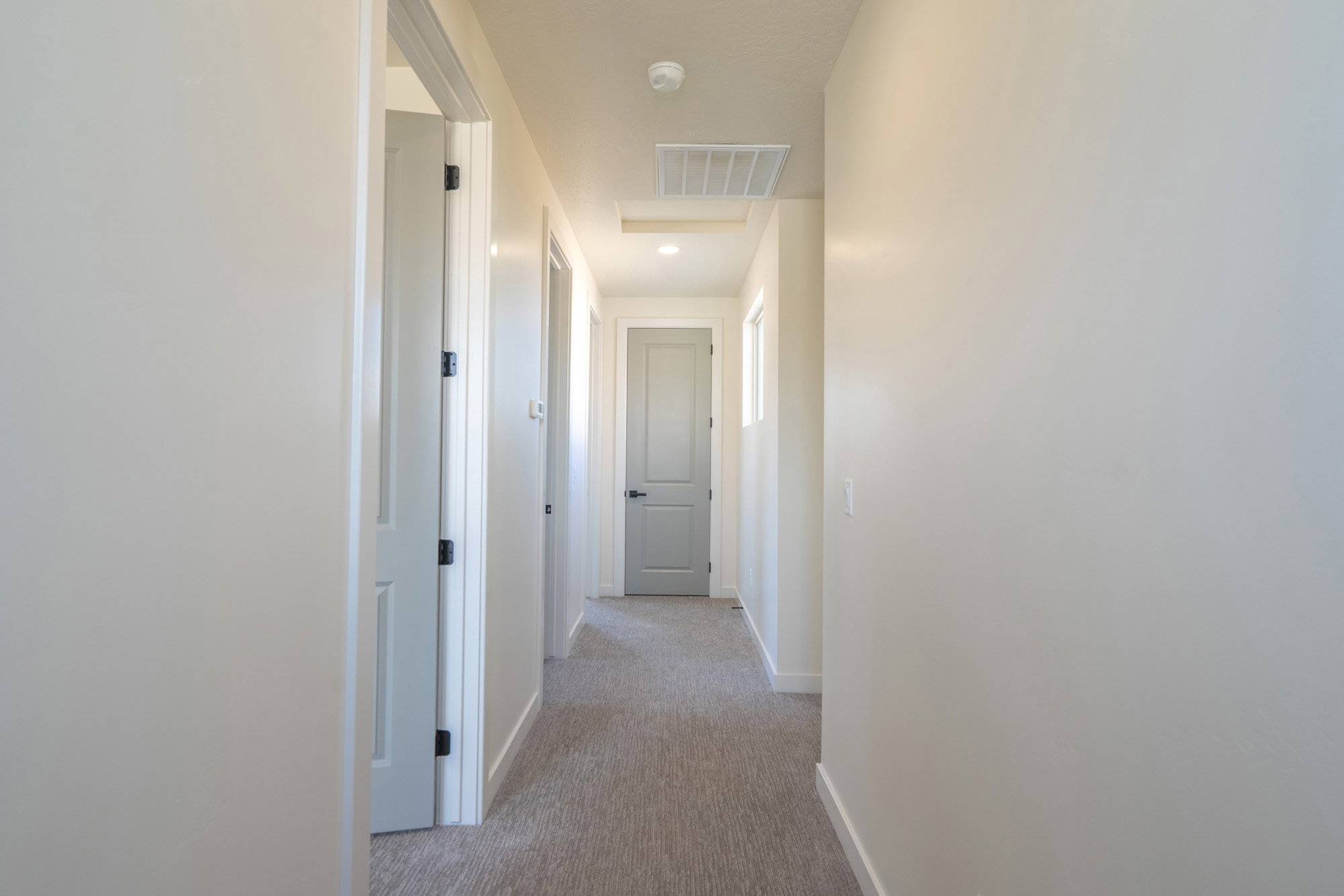 Hallway featuring light neutral wall paint, gray carpet flooring, recessed lighting, and white trim