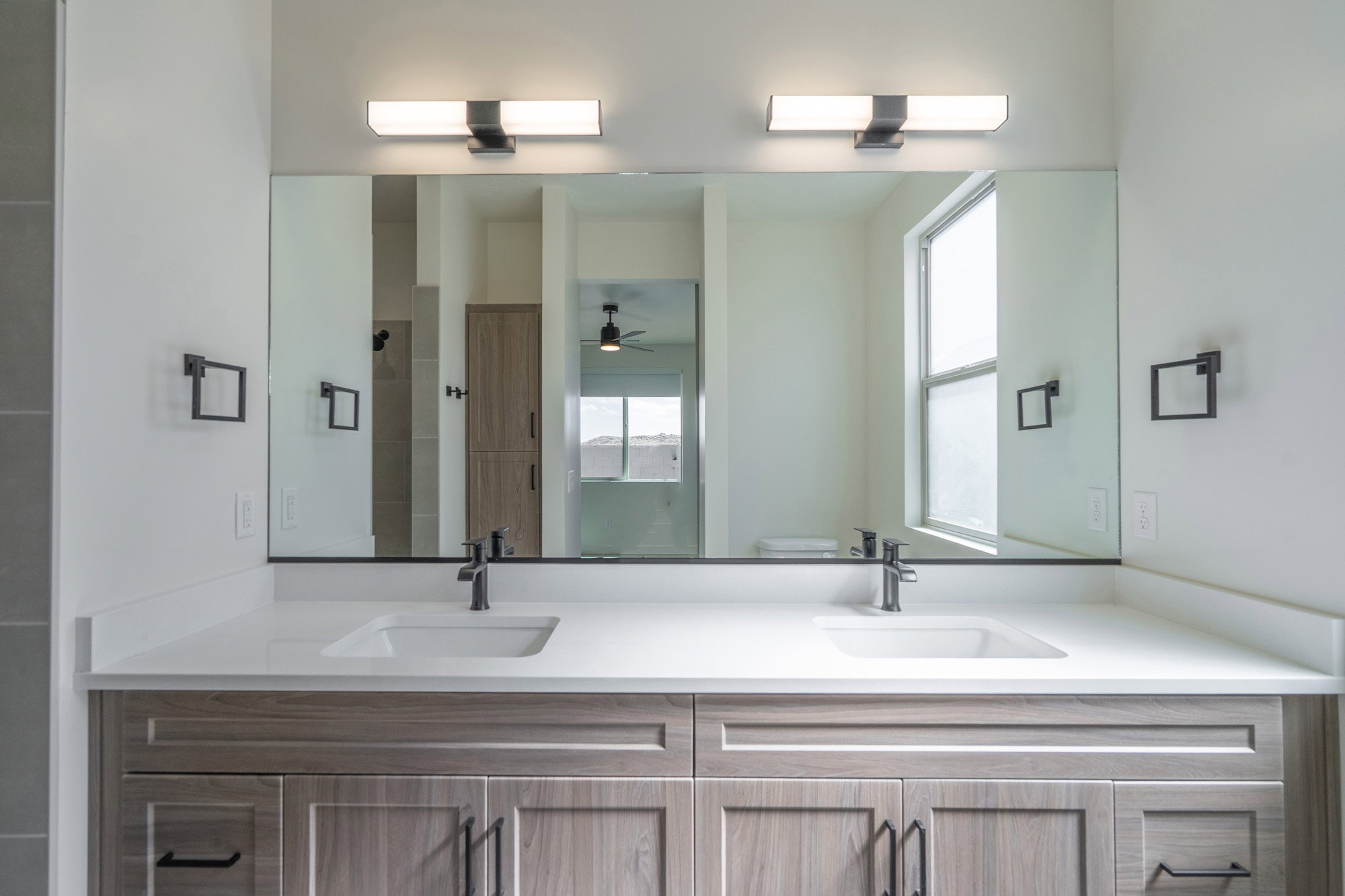 Dual vanity featuring wood-finish cabinetry, white countertops, and integrated rectangular sinks
