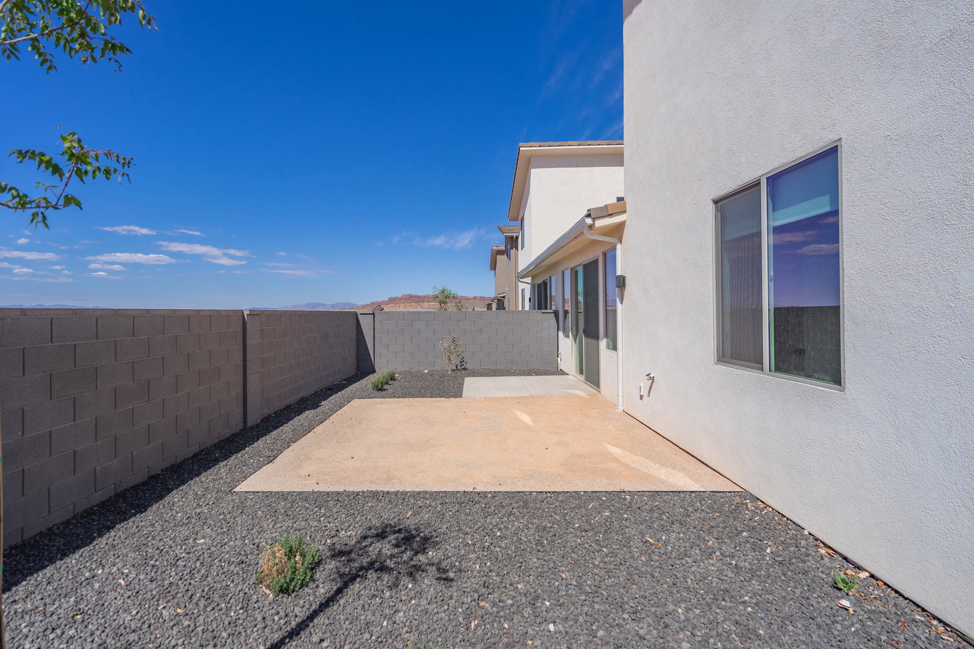 Private backyard featuring a concrete patio, perimeter block wall fencing, and a gravel ground cover