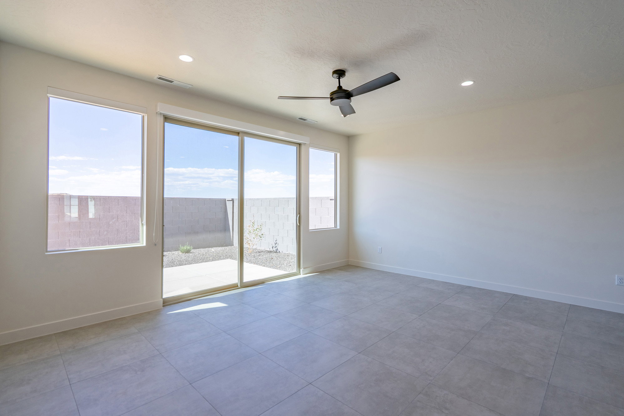 Open-concept room featuring large format tile flooring, a sliding glass door to the rear patio, and multiple windows