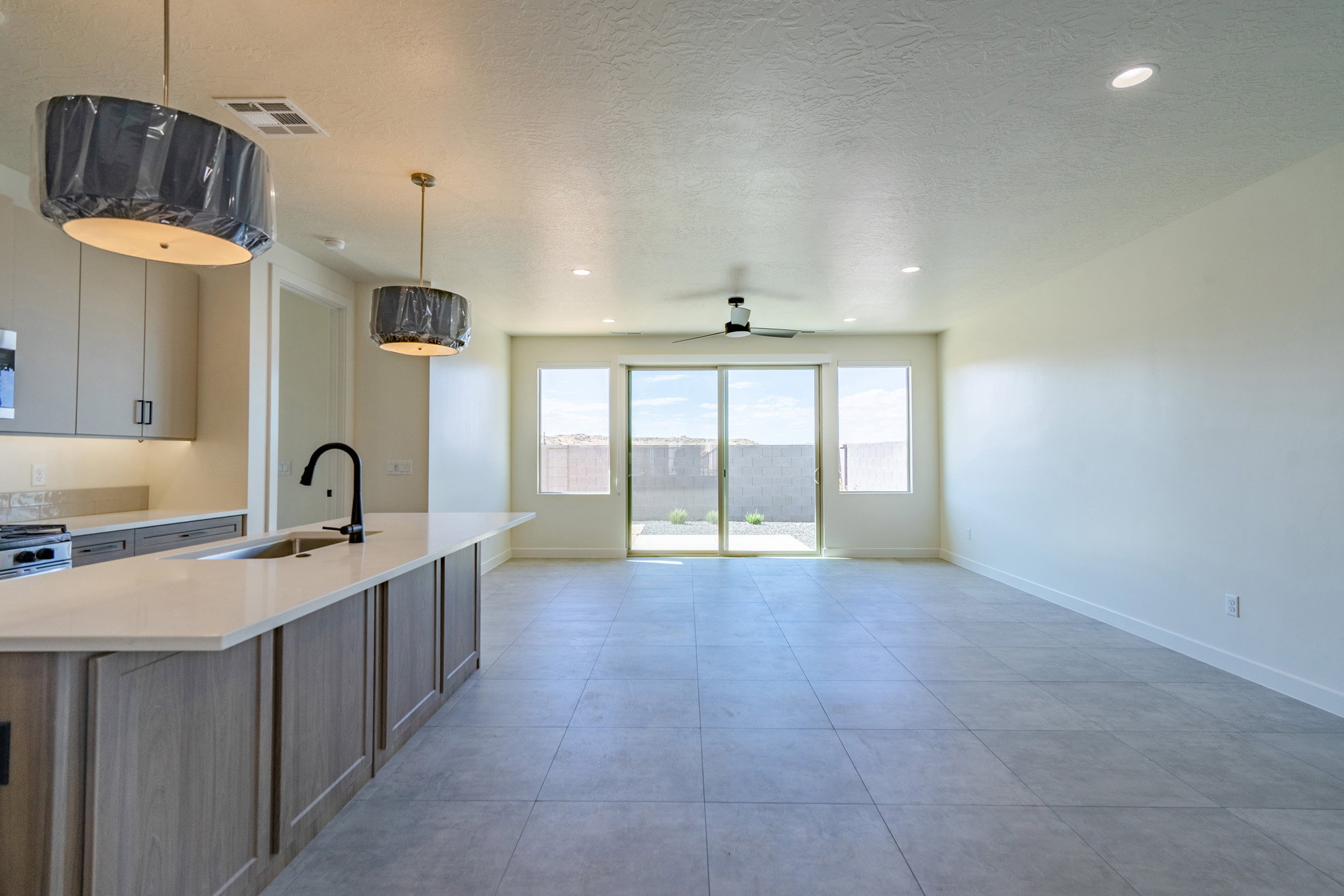 Open-concept living space featuring a kitchen island with sink, contemporary pendant lighting, and light-toned cabinetry
