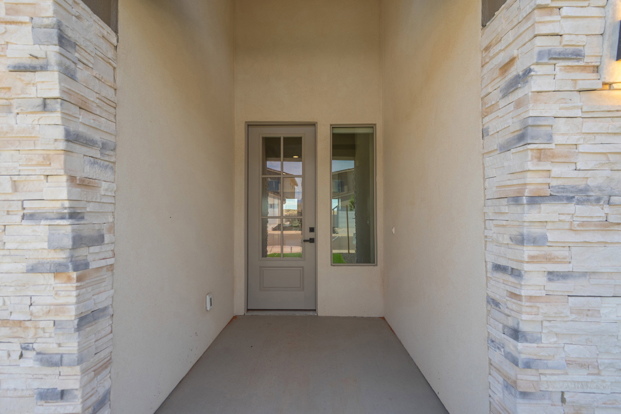 Recessed entryway featuring a stucco finish, stacked stone accents, a full-lite door with divided lites, and a sidelite window