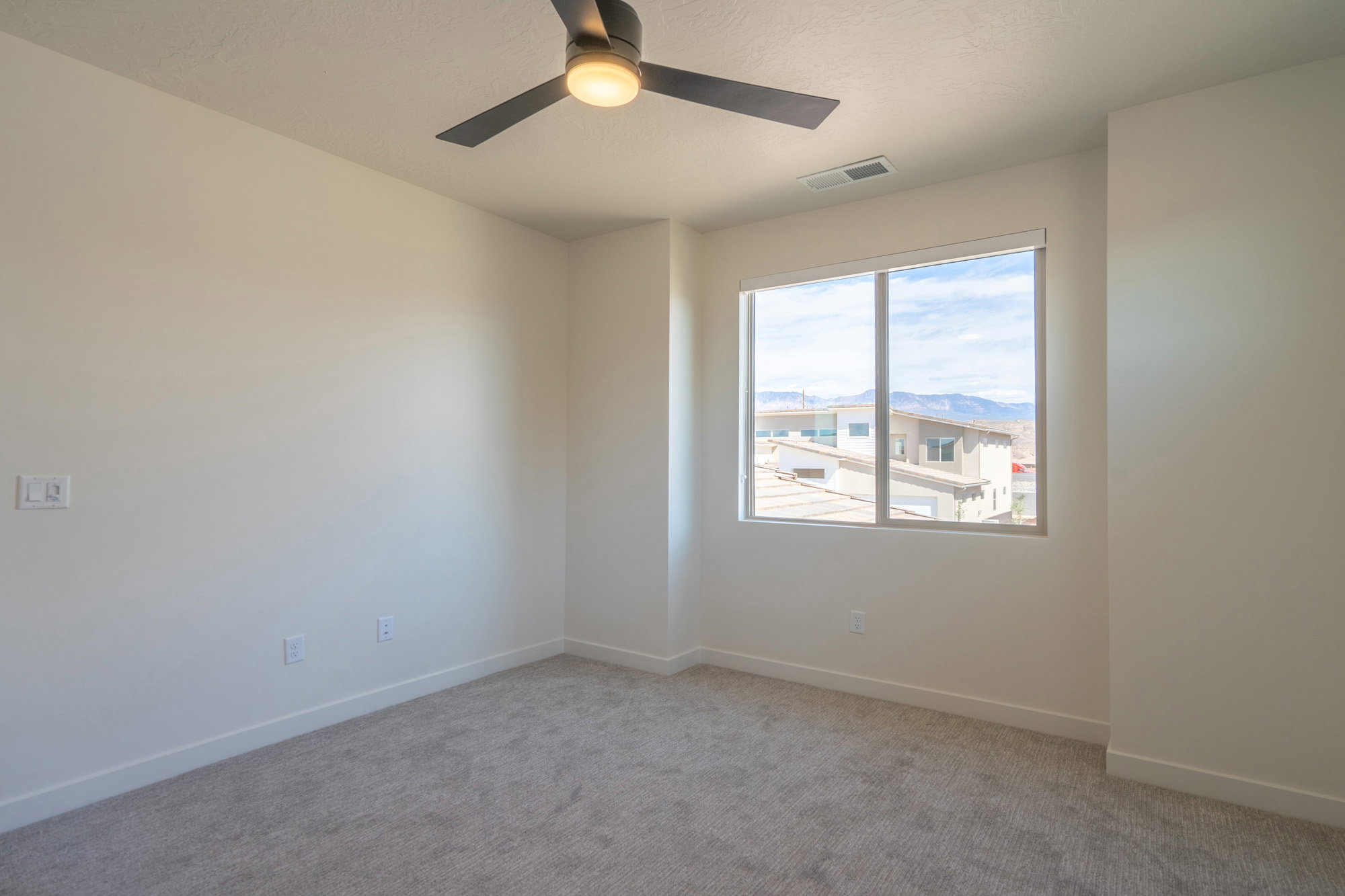 Neutral tone walls with light gray carpeting, featuring a modern ceiling fan with integrated lighting