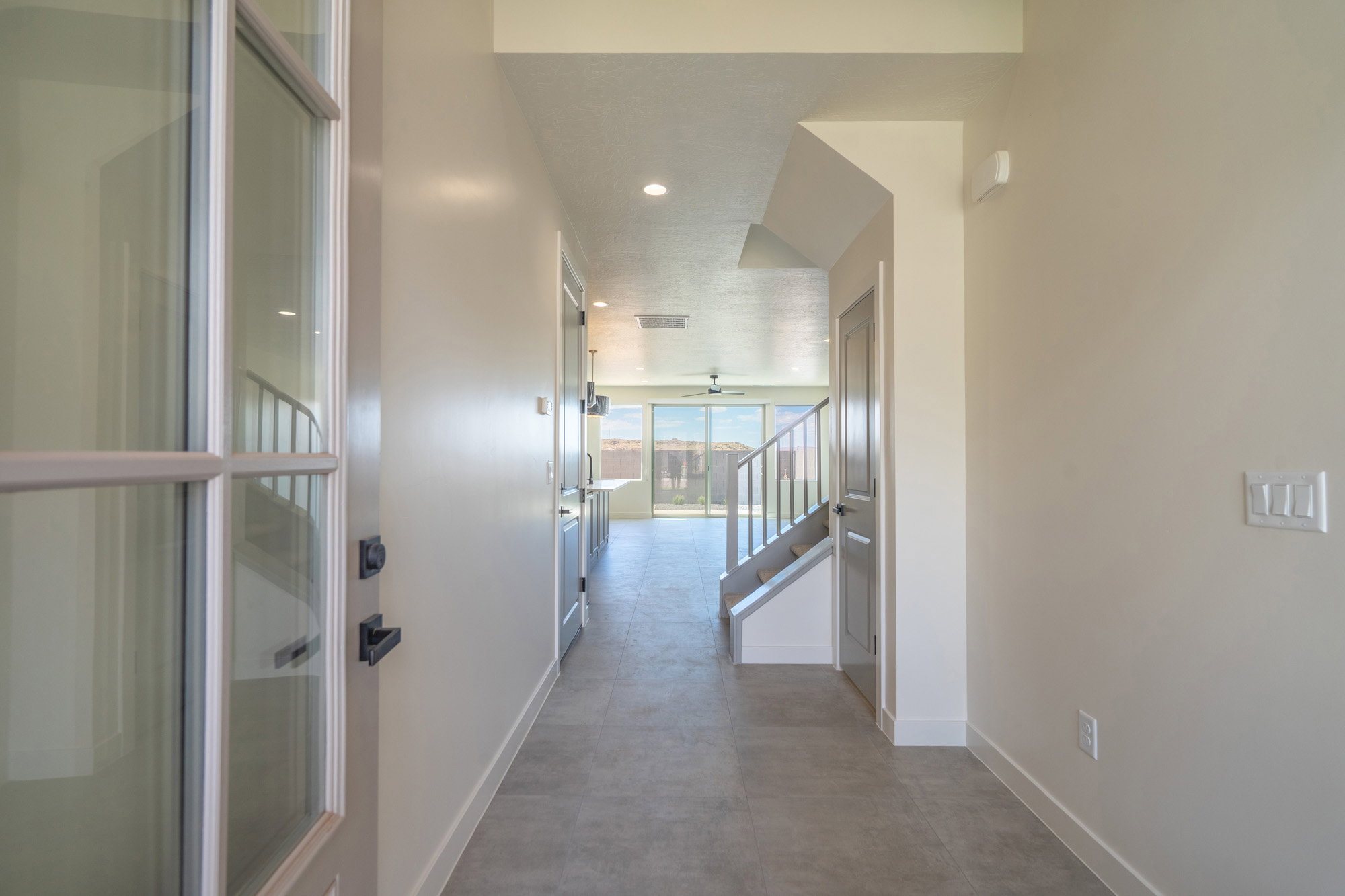 Spacious entryway featuring a glass-paneled door, recessed lighting, tile flooring, and a modern staircase with a metal railing