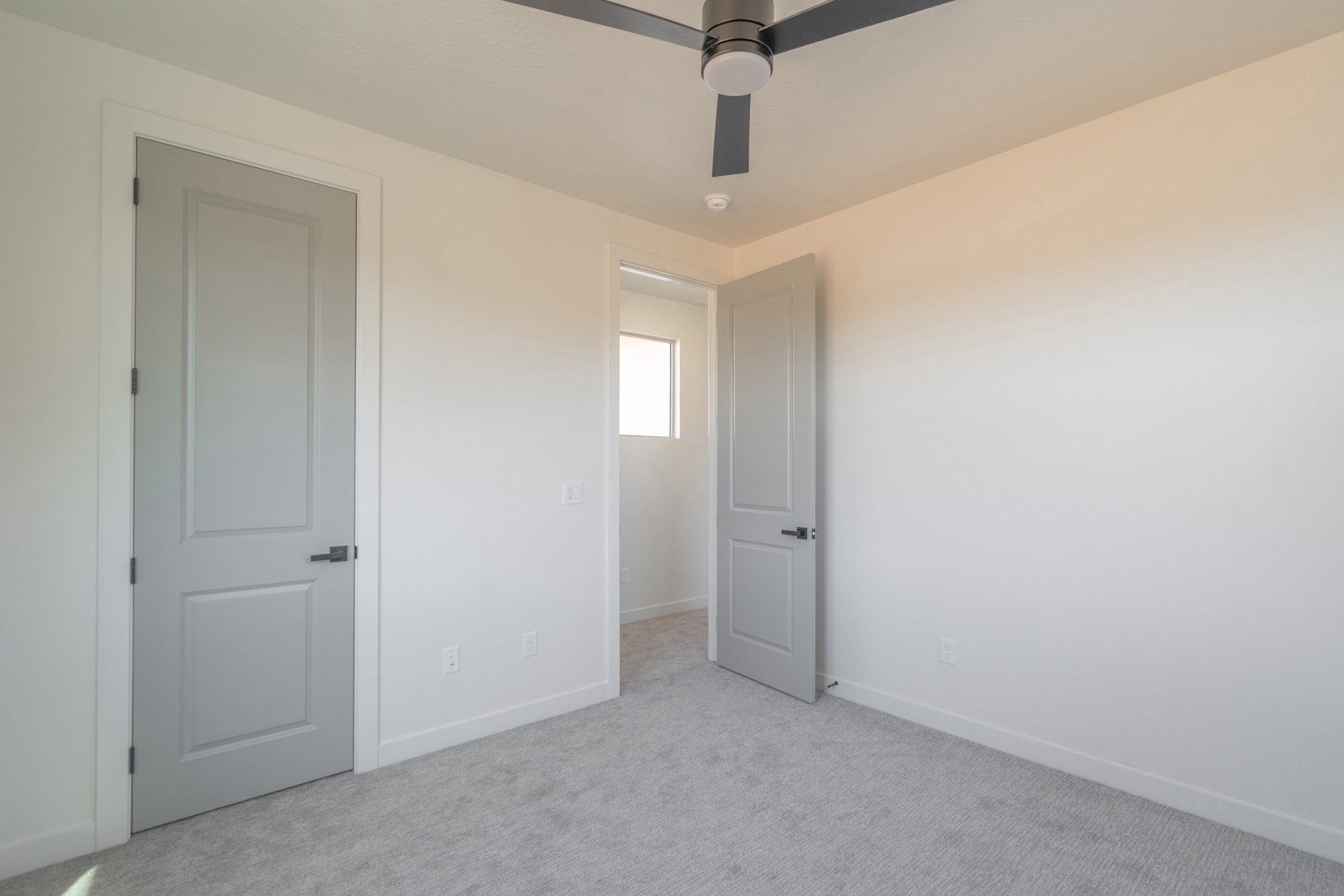 Bedroom featuring light grey carpeting, white walls, and a modern ceiling fan with integrated lighting