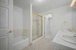 Bathroom featuring a dual vanity, gold-framed glass shower enclosure, and a built-in bathtub with tiled surround
