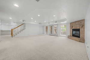 Spacious room featuring light-toned carpeting, a brick fireplace, and double glass doors