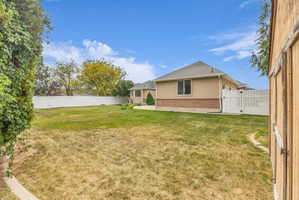 Expansive backyard featuring a large lawn area, full privacy fencing, and a separate storage shed
