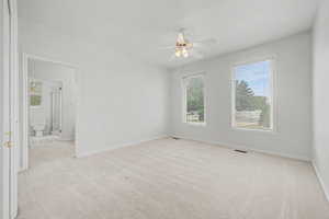 Carpeted room with white walls, two windows featuring horizontal blinds, and a ceiling fan with integrated lighting