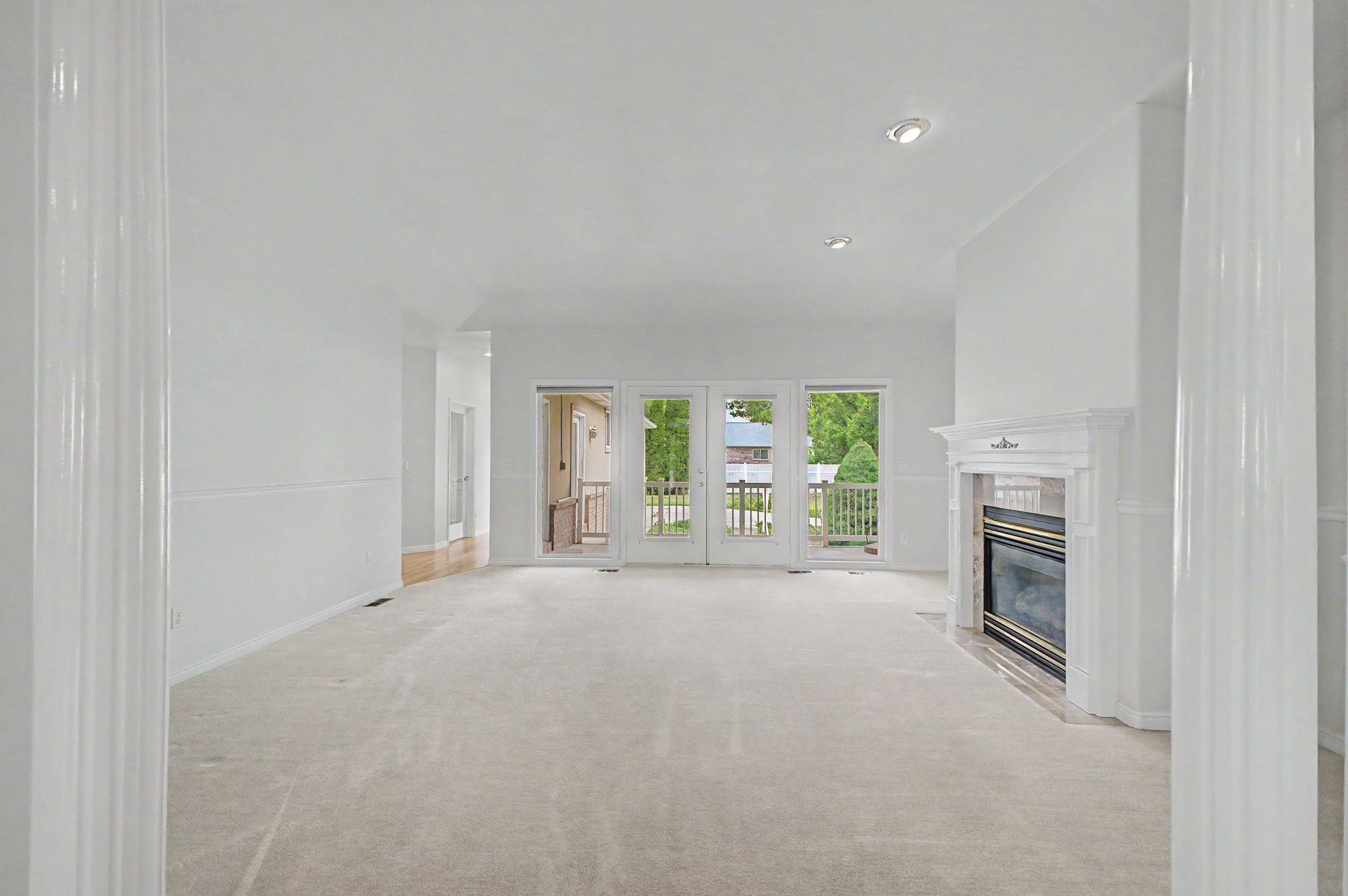 Spacious living area featuring light-colored carpeting, a white mantel fireplace, and recessed lighting