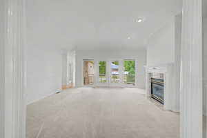 Spacious living area featuring light-colored carpeting, a white mantel fireplace, and recessed lighting