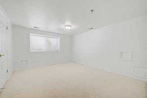 Spacious room featuring neutral carpeting, white walls, and a window with horizontal blinds